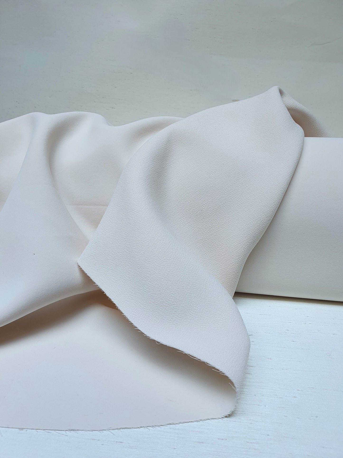 Close-up of heavy double-backed fabric in cream white, soft texture visible 