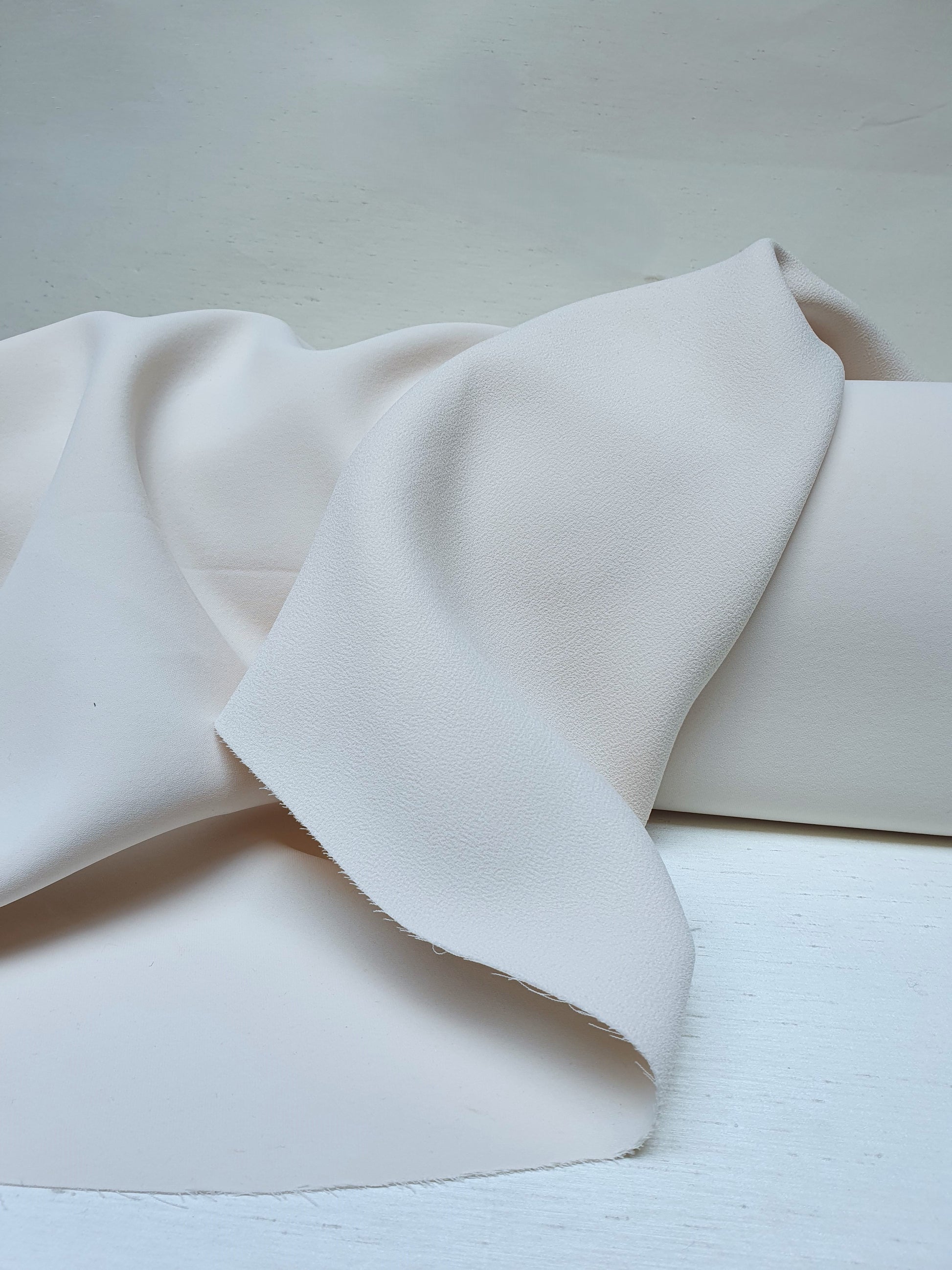 Close-up of heavy double-backed fabric in cream white, soft texture visible 