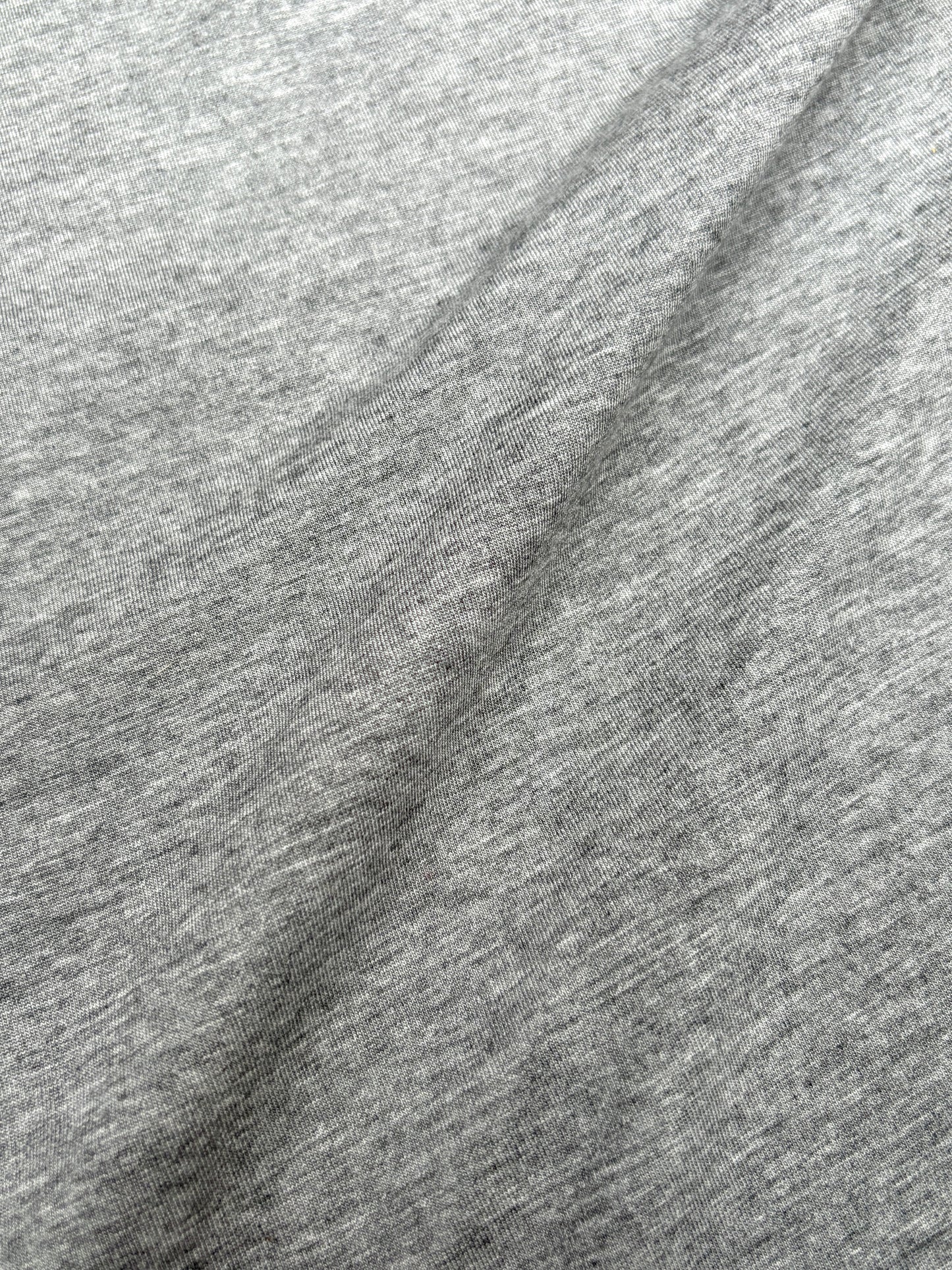 Close-up of light weighted jersey fabric in grey, soft texture visible 