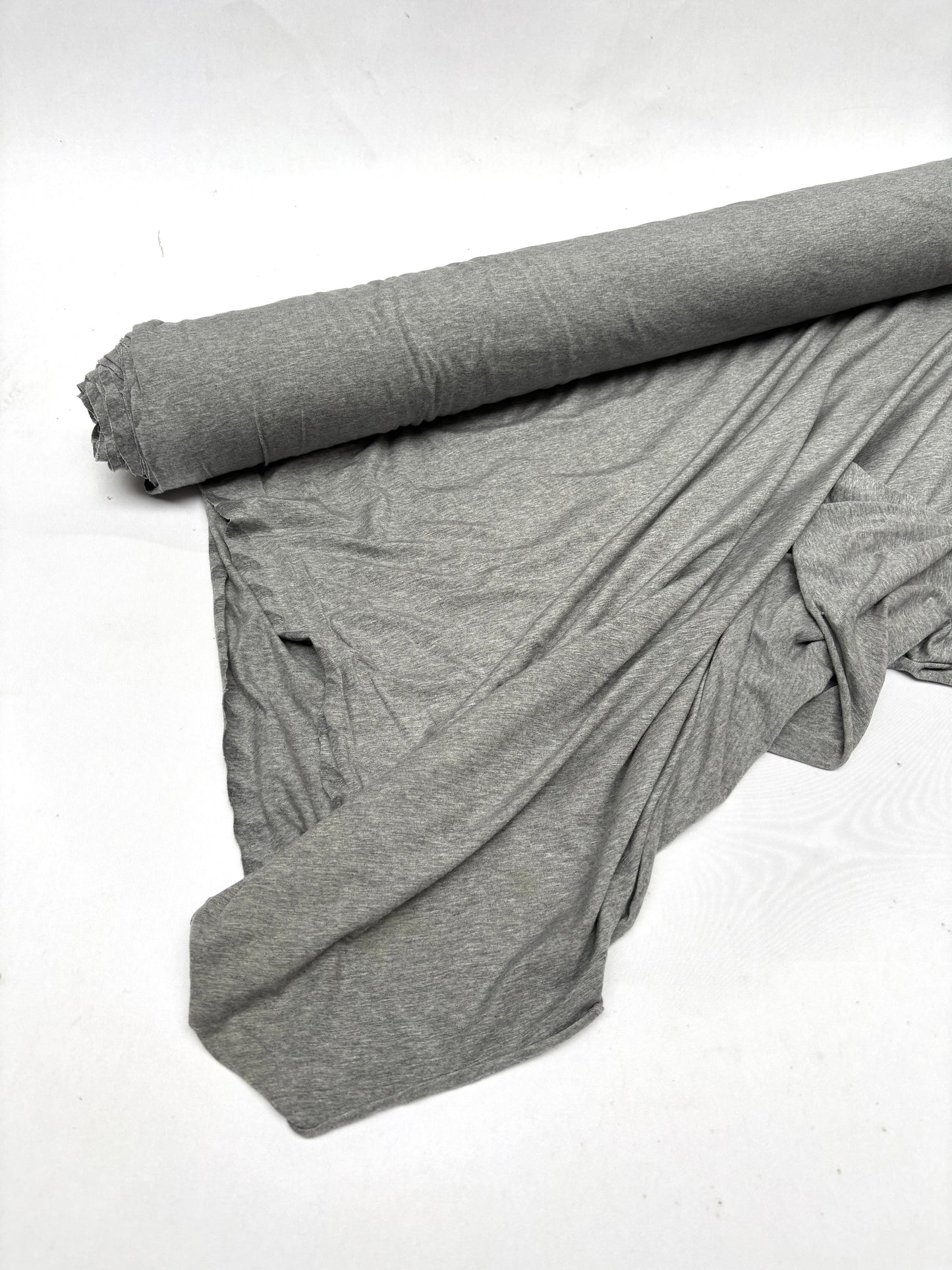 Roll of light weighted jersey fabric in grey, soft texture visible 