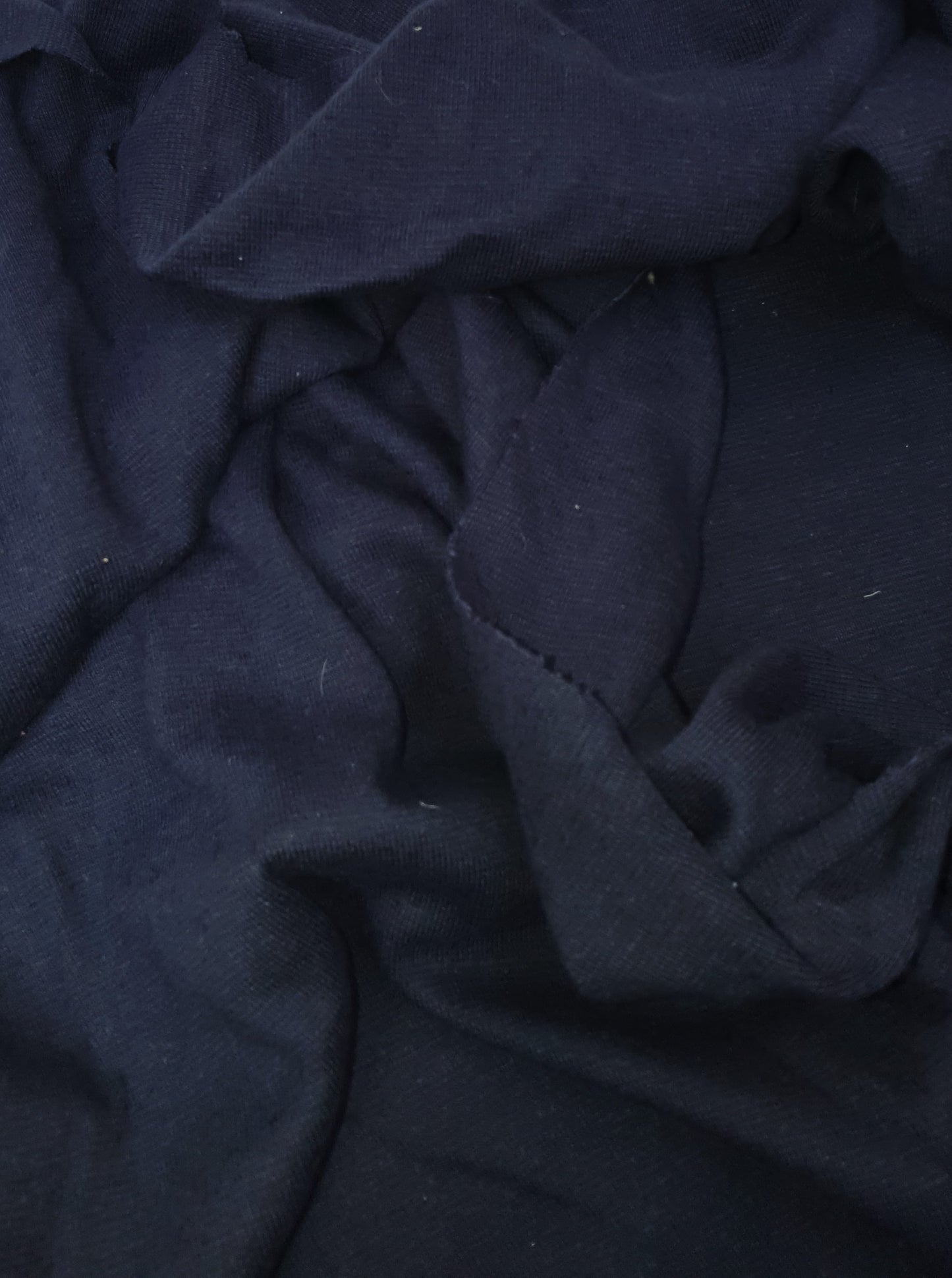 Close-up of light weighted jersey fabric in navy, soft texture visible 