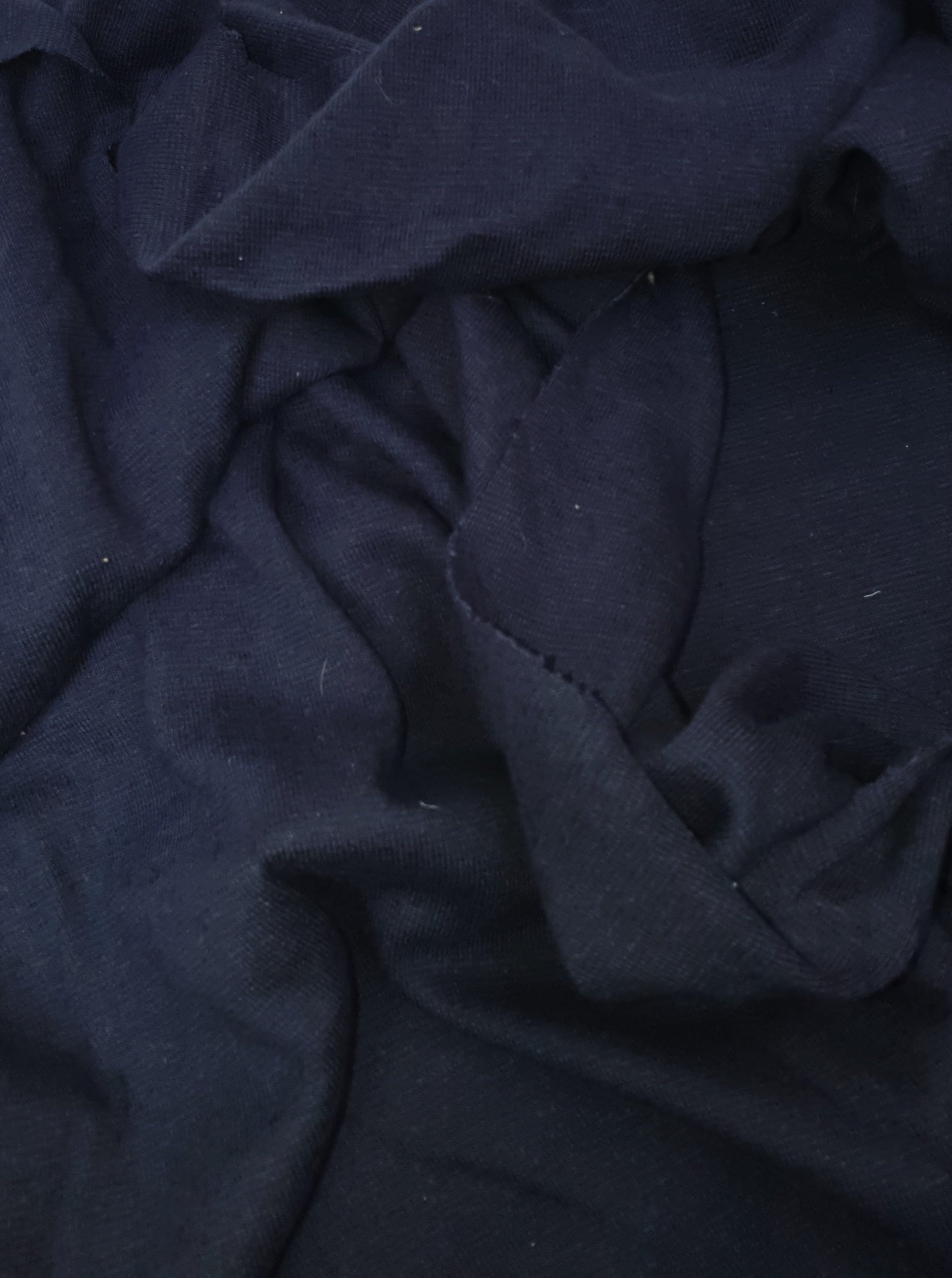 Close-up of light weighted jersey fabric in navy, soft texture visible 