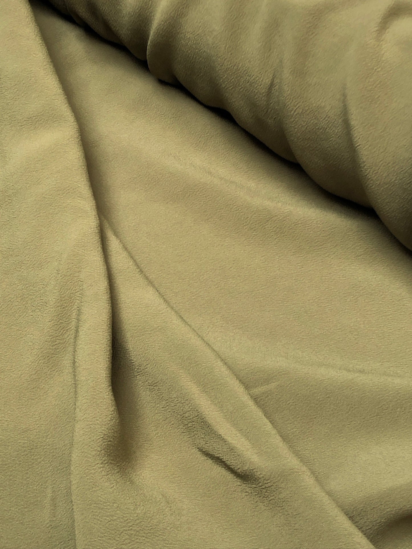Close-up of light weighted crape fabric in olive green 