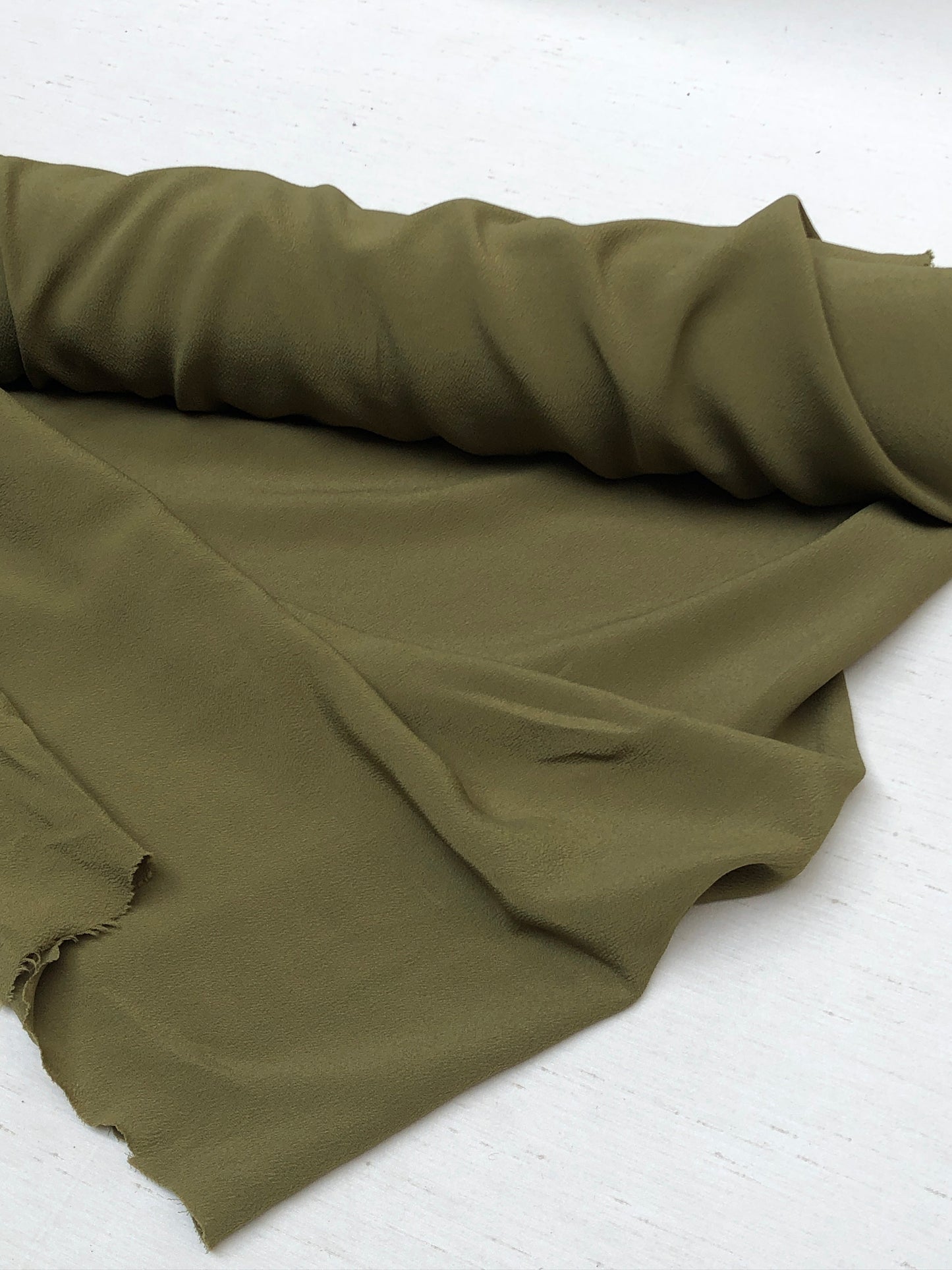 Roll of light weighted crape fabric in olive green 