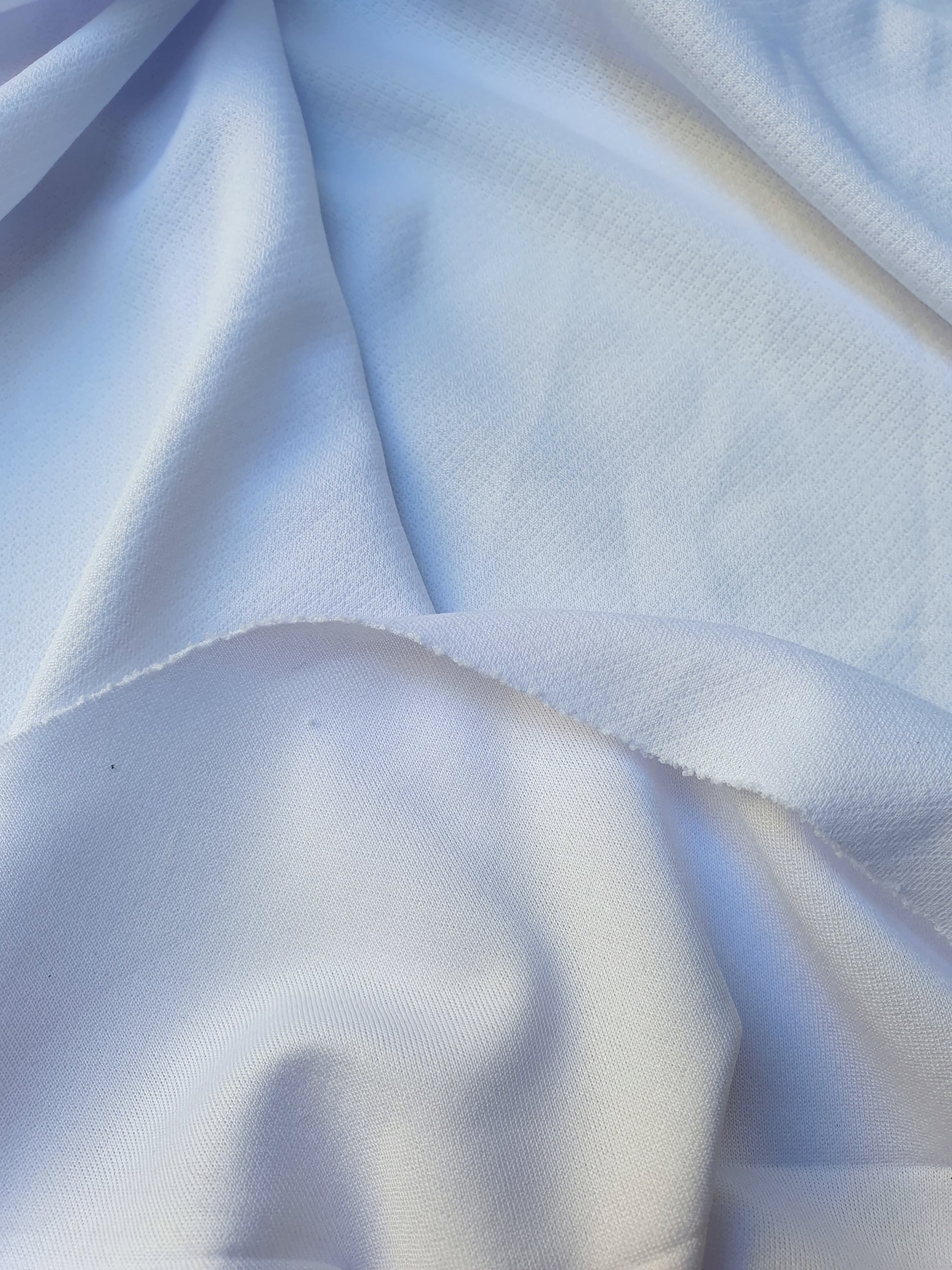 Close-up of jersey light weight fabric in white, soft texture visible 