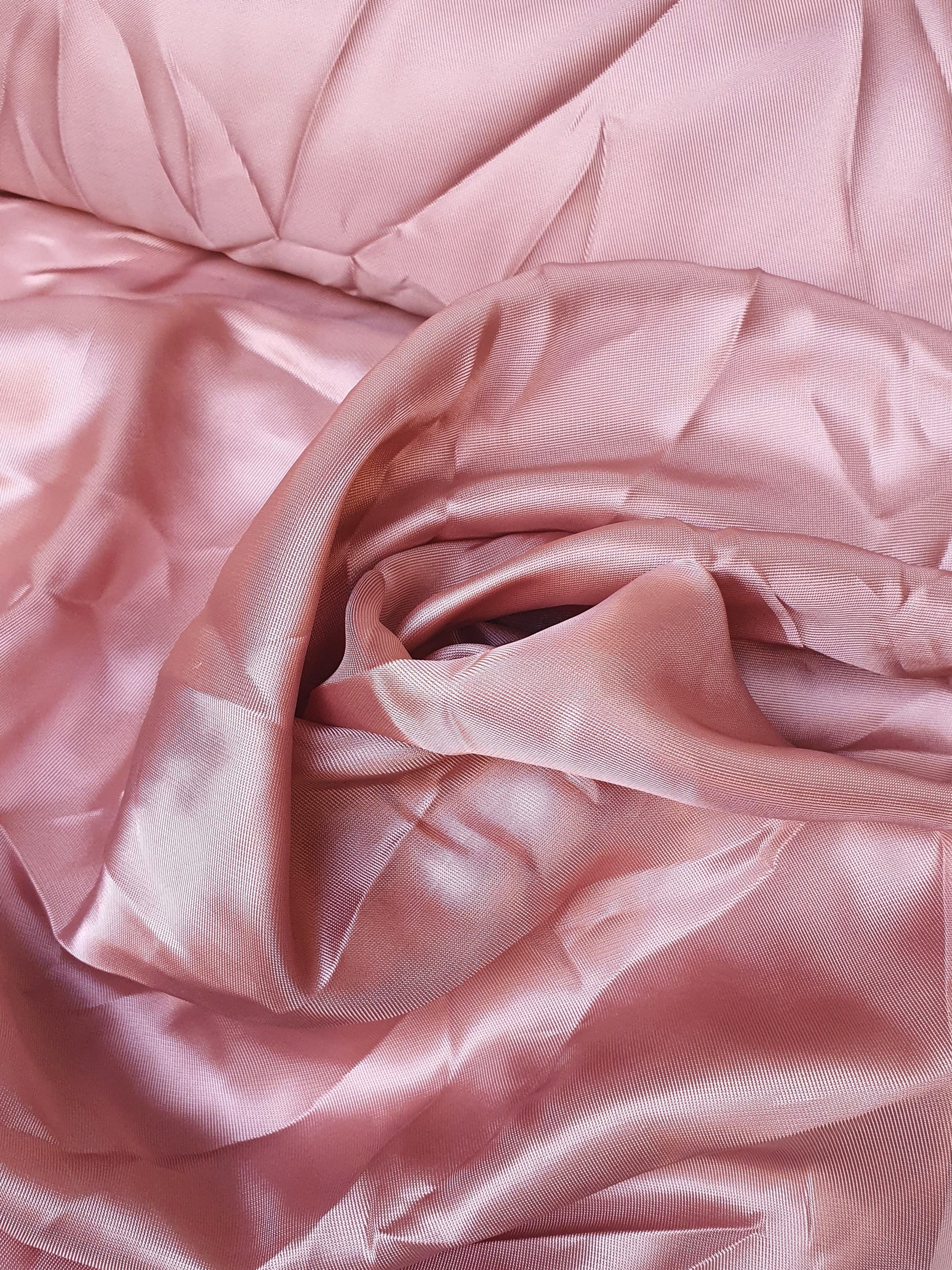 Close-up of satin twill fabric in pink, shiny texture visible 