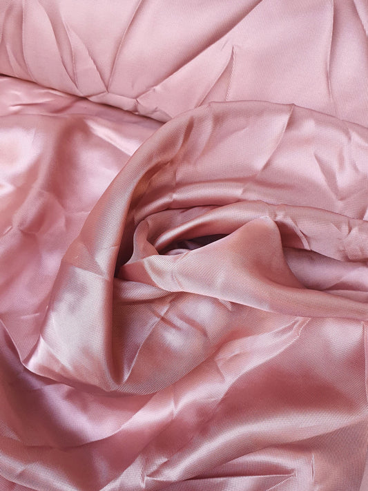 Close-up of satin twill fabric in pink, shiny texture visible 