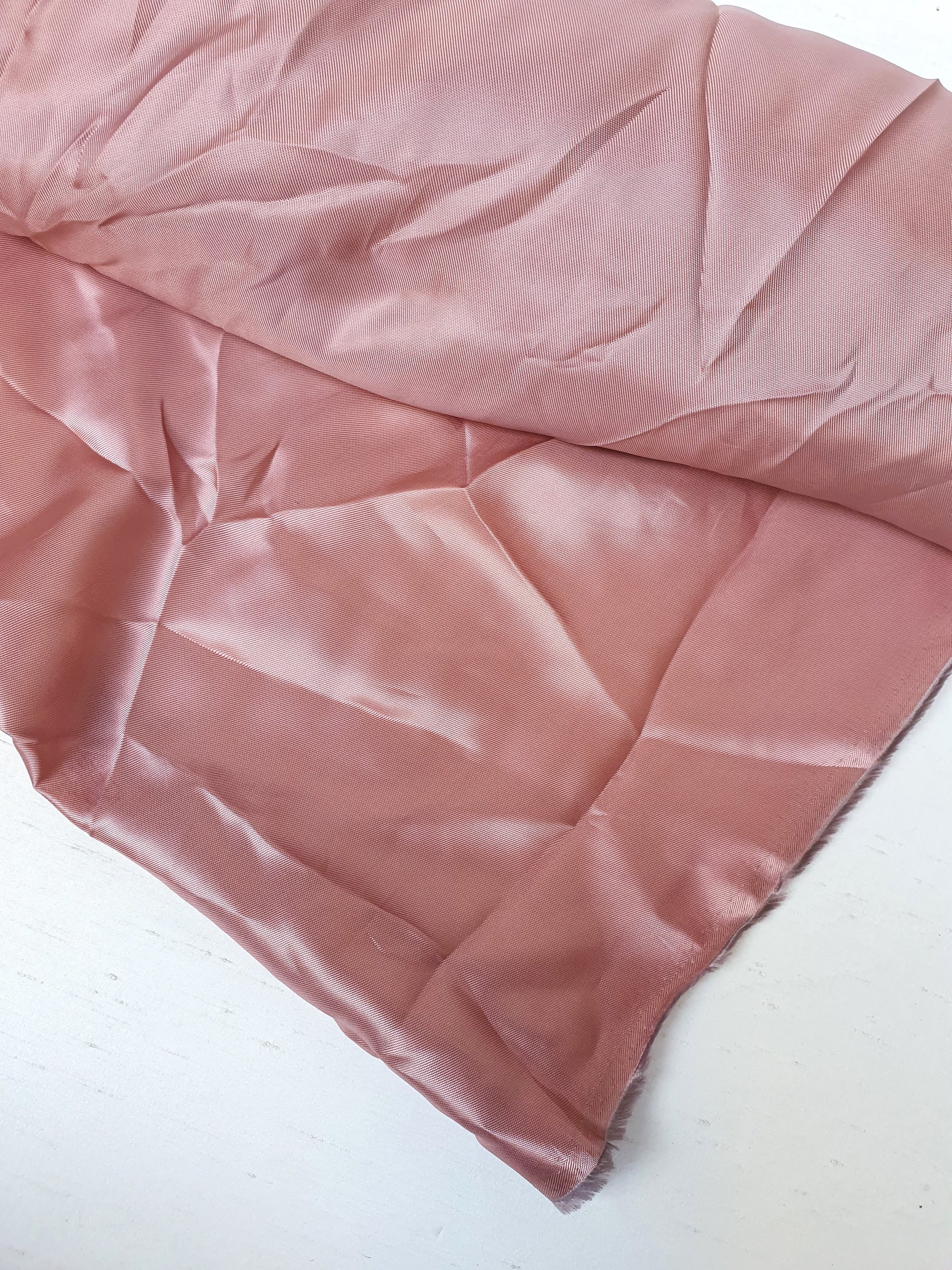 Satin twill fabric in pink, shiny texture visible 