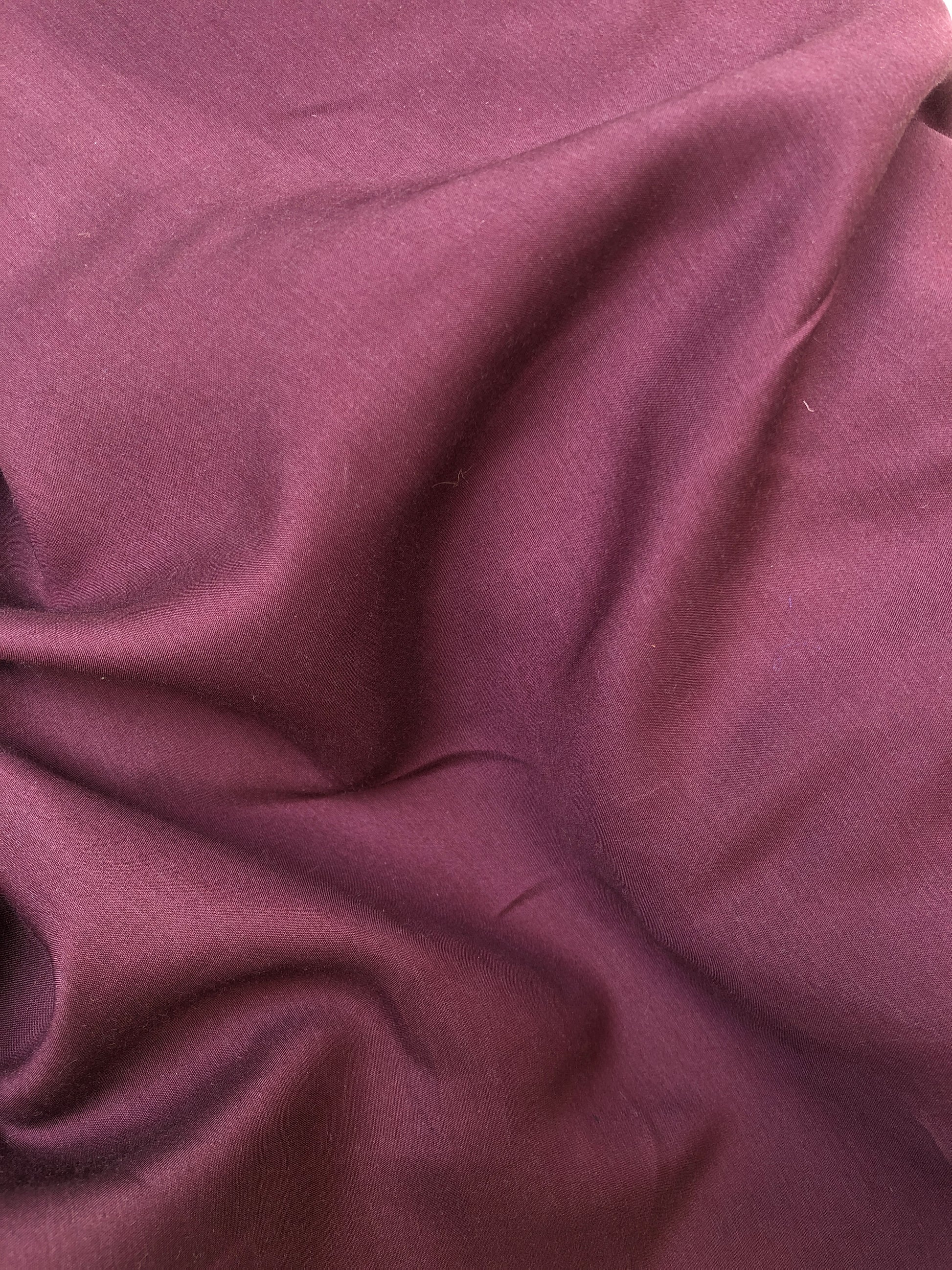 Close-up of wool suiting twill fabric in burgundy, soft texture visible 