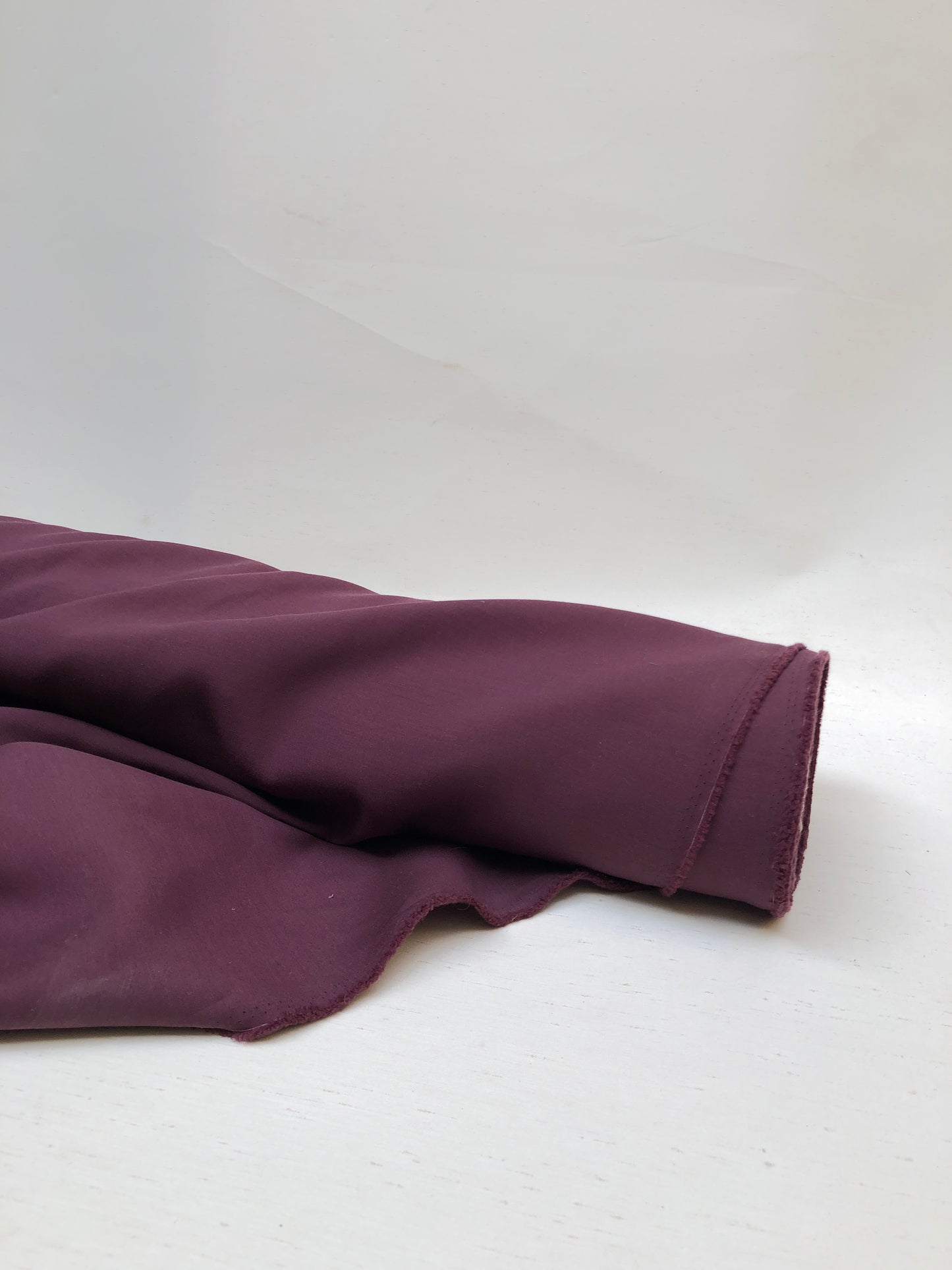 Roll of wool suiting twill fabric in burgundy