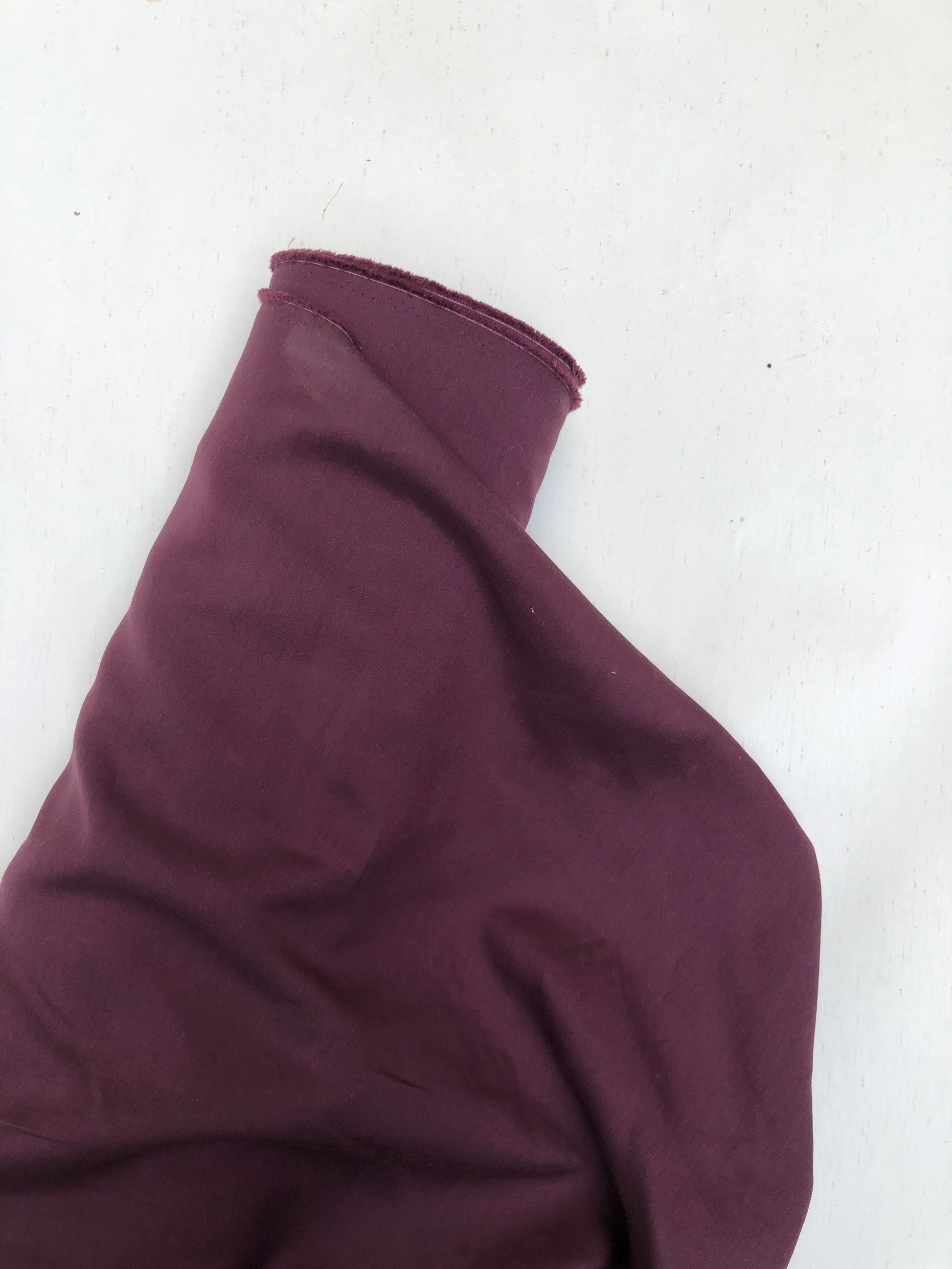 Roll of wool suiting twill fabric in burgundy