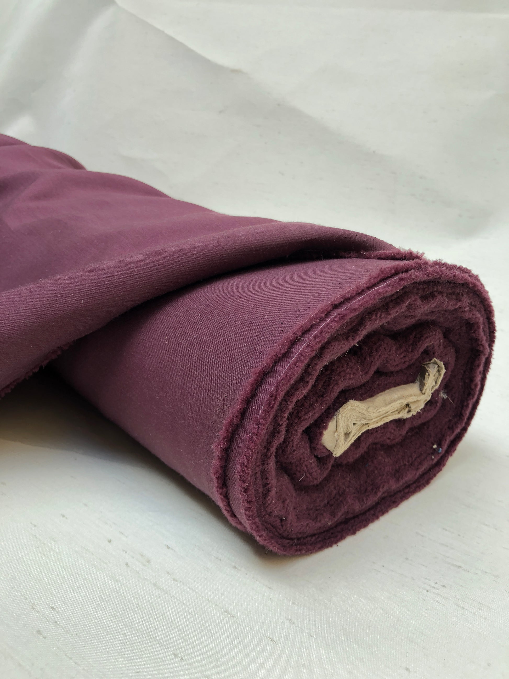 Roll of wool suiting twill fabric in burgundy