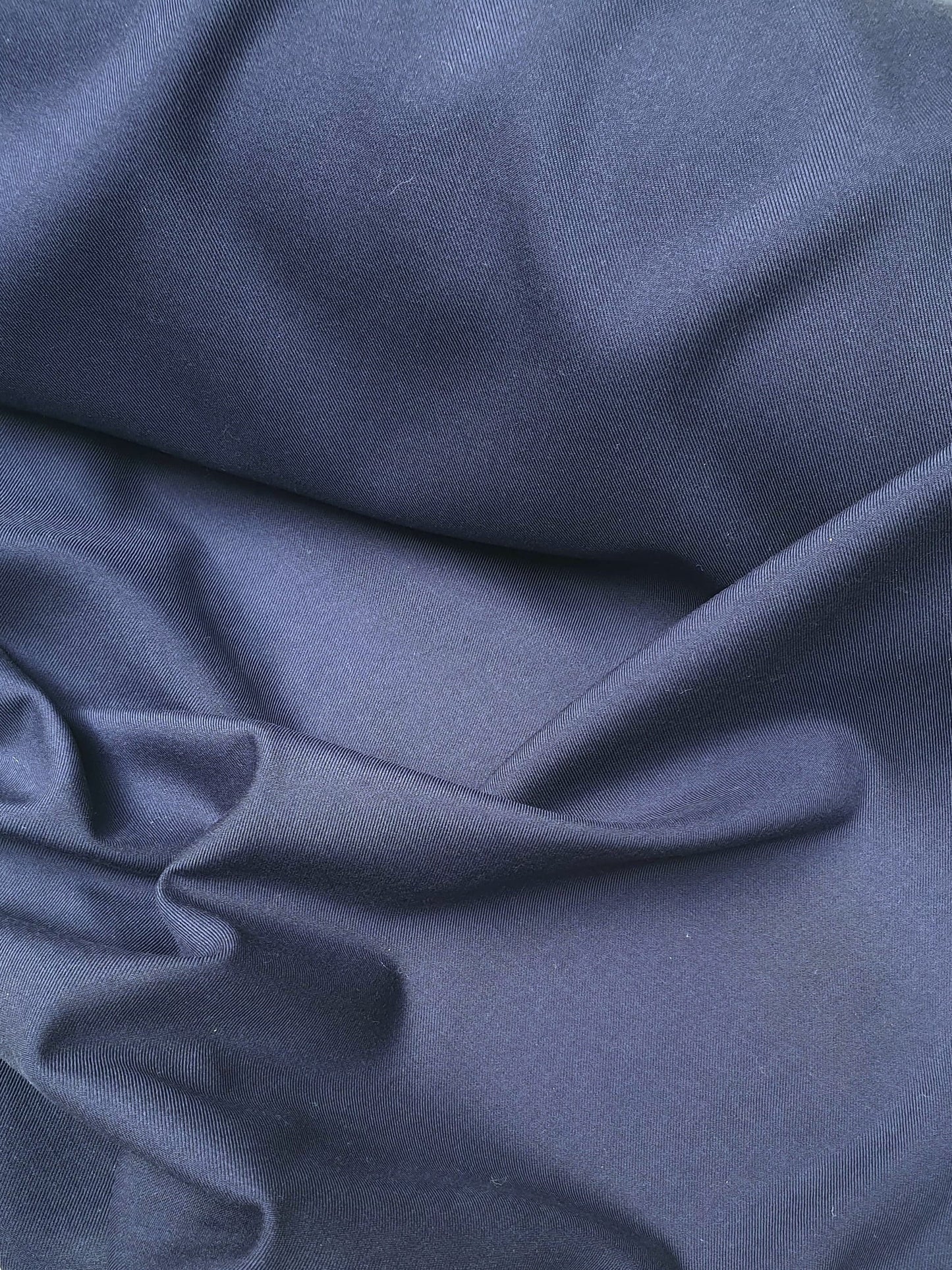 Close-up of wool suiting twill fabric in navy, shiny texture visible 