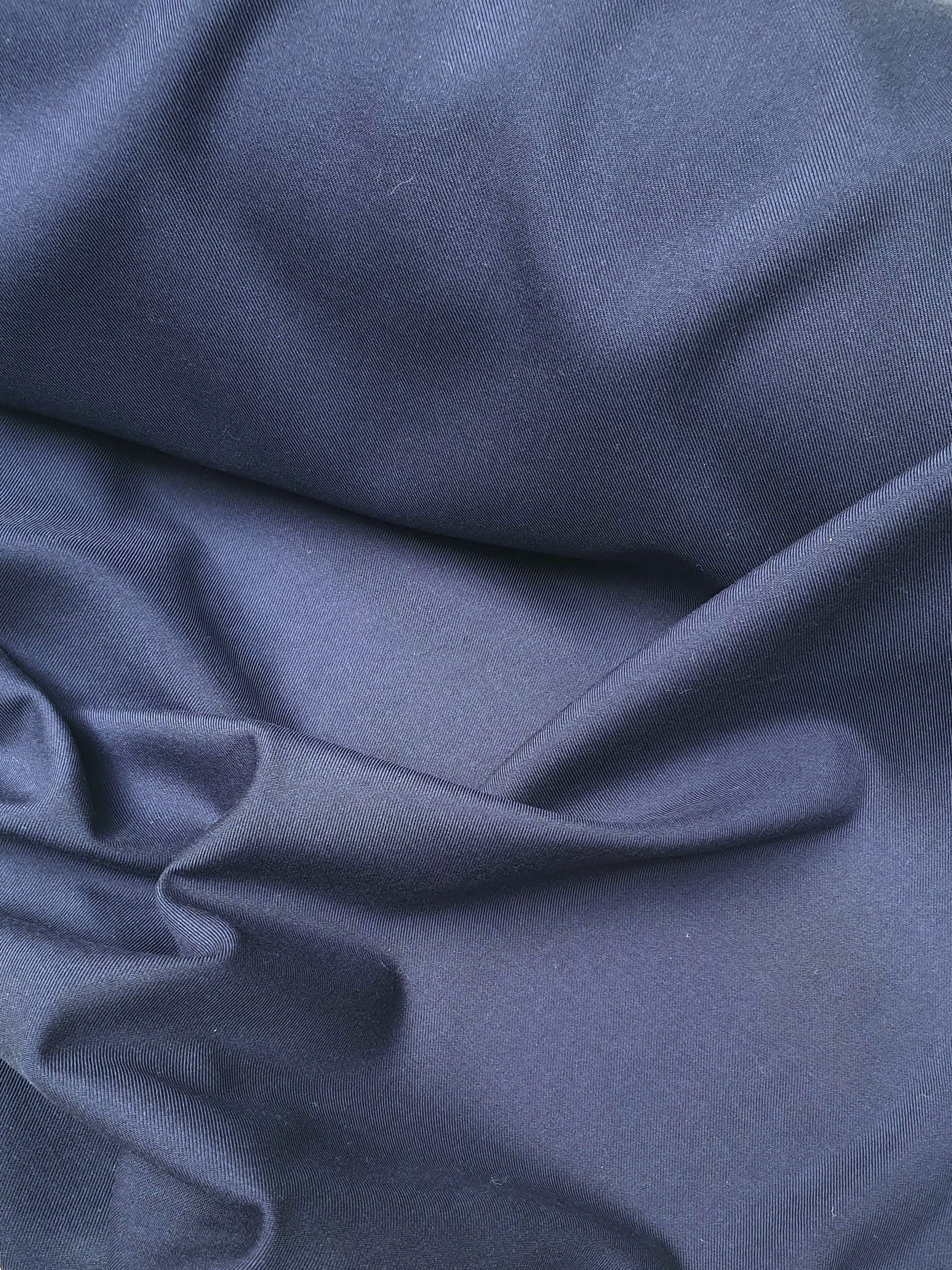 Close-up of wool suiting twill fabric in navy, shiny texture visible 