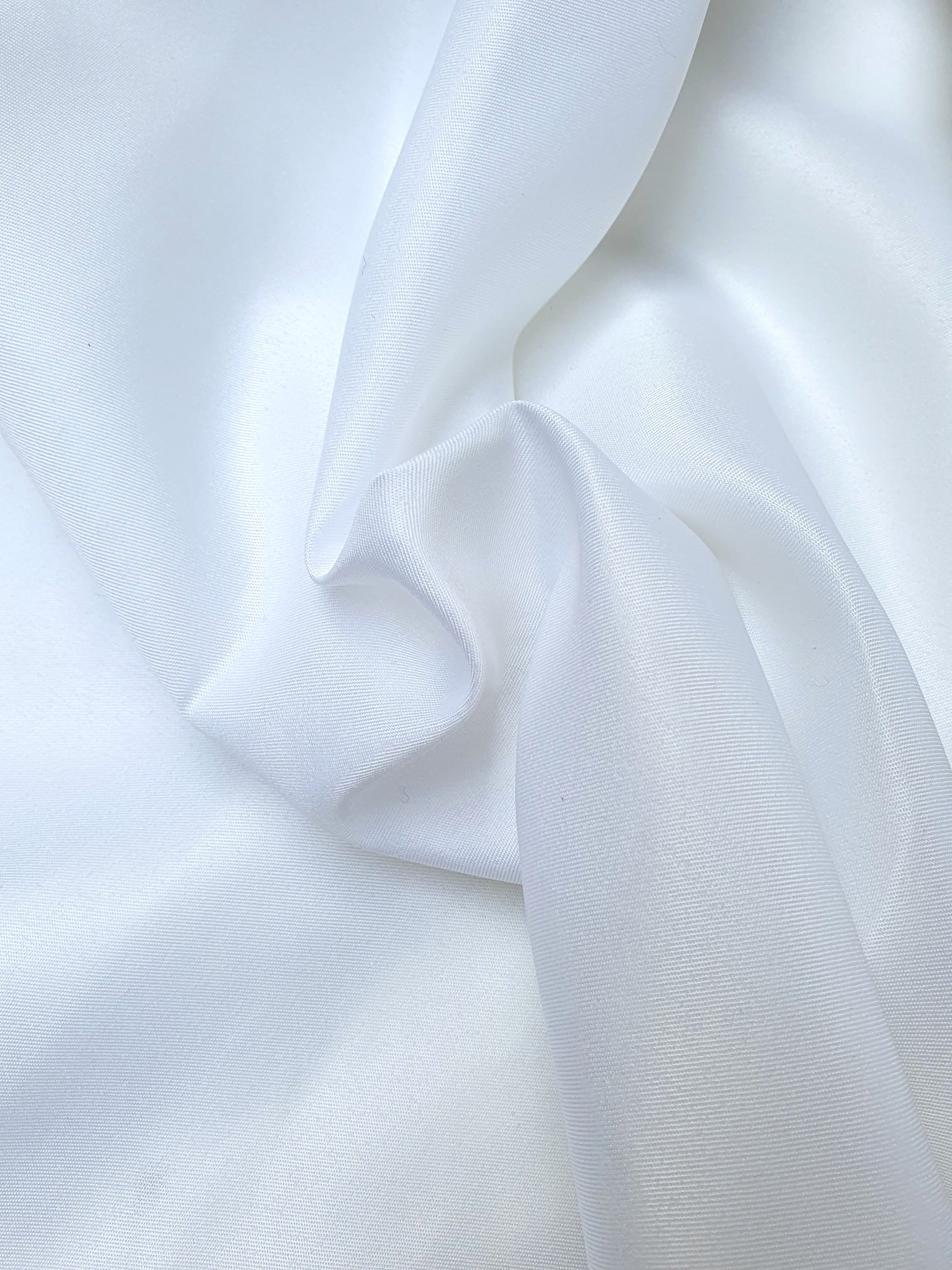 Close-up of shiny polyester taffeta fabric in white, soft texture visible 