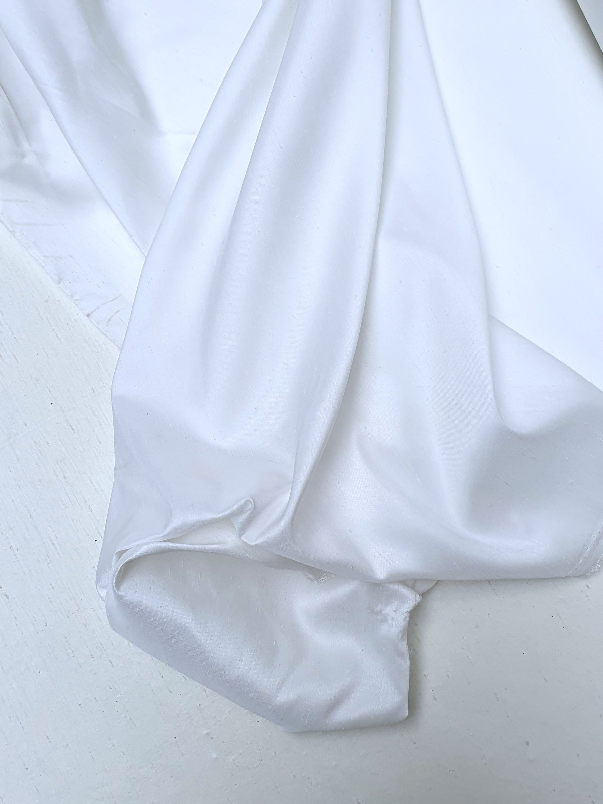 Close-up of shiny polyester taffeta fabric in white, soft texture visible 