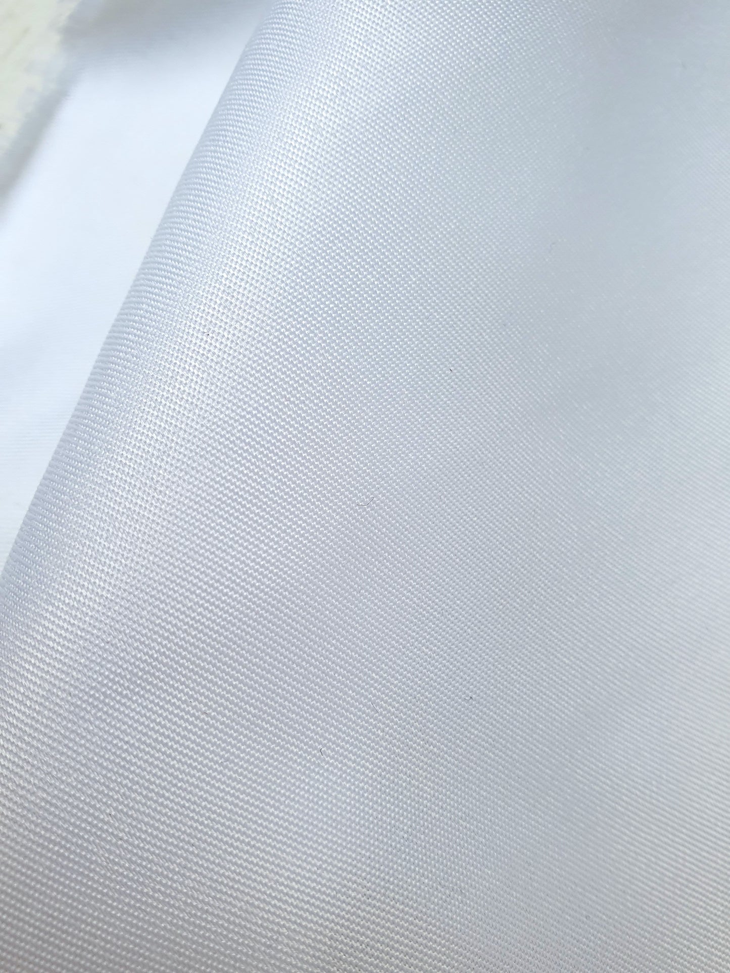 Close-up of shiny polyester taffeta fabric in white, soft texture visible 
