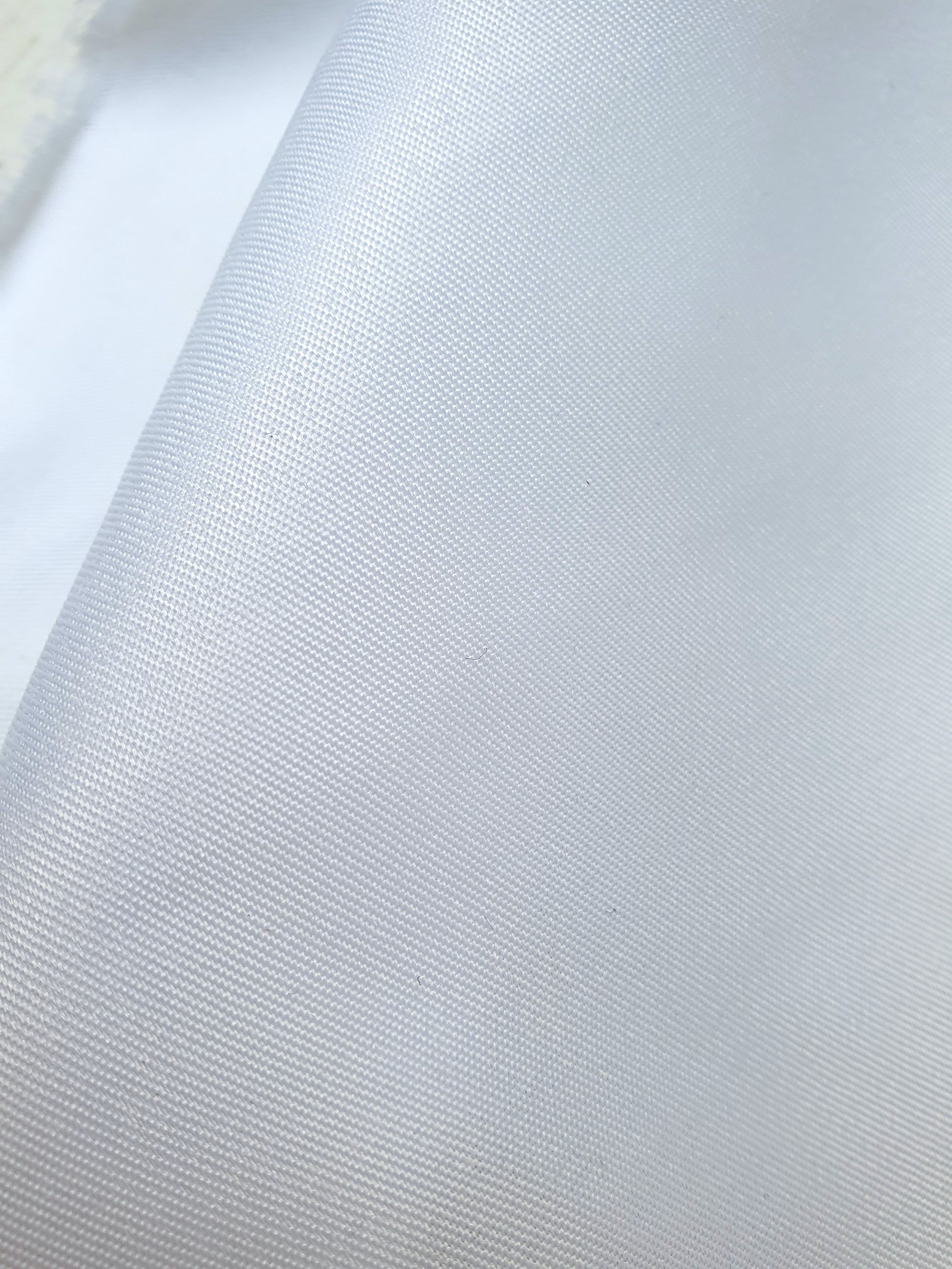 Close-up of shiny polyester taffeta fabric in white, soft texture visible 