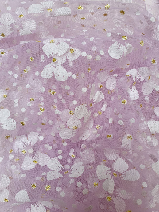 Close-up of a roll of floral printed transparent mesh fabric in purple, soft texture visible 