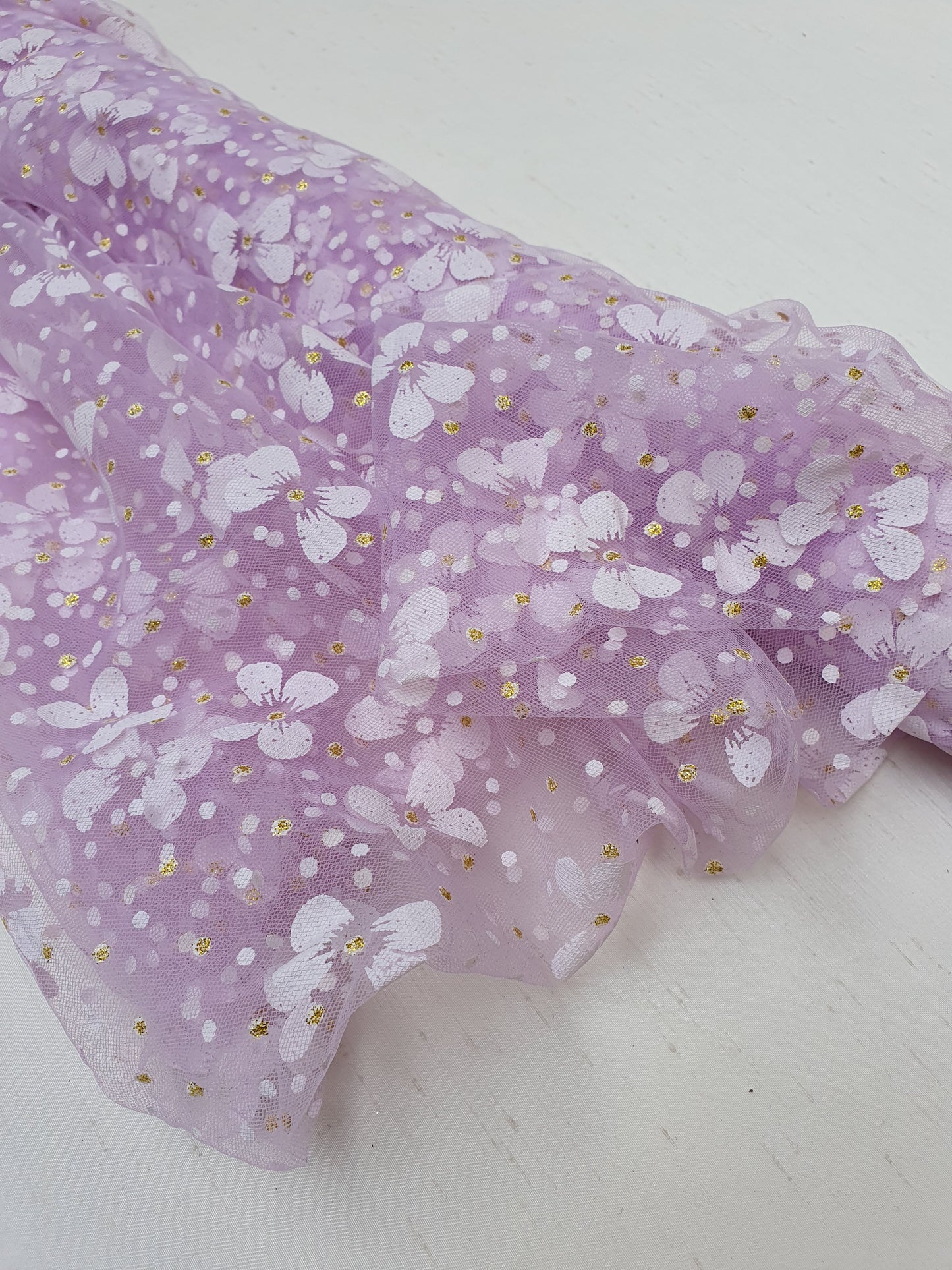Close-up of a roll of floral printed transparent mesh fabric in purple