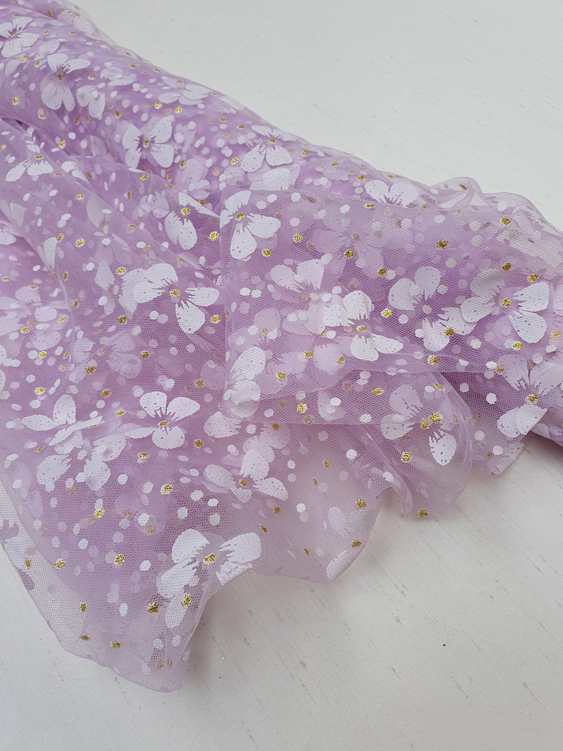 Close-up of a roll of floral printed transparent mesh fabric in purple