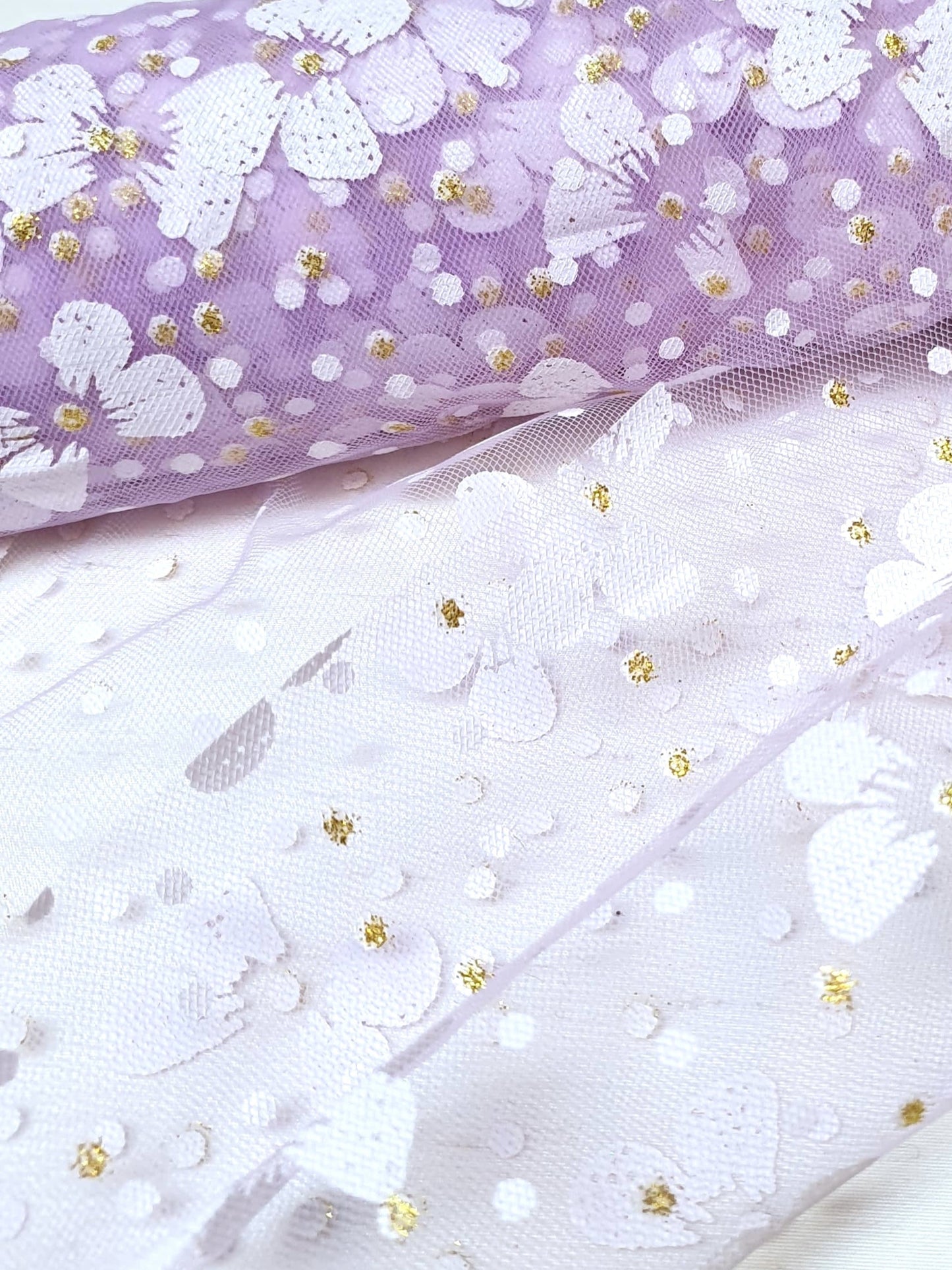 Close-up of a roll of floral printed transparent mesh fabric in purple
