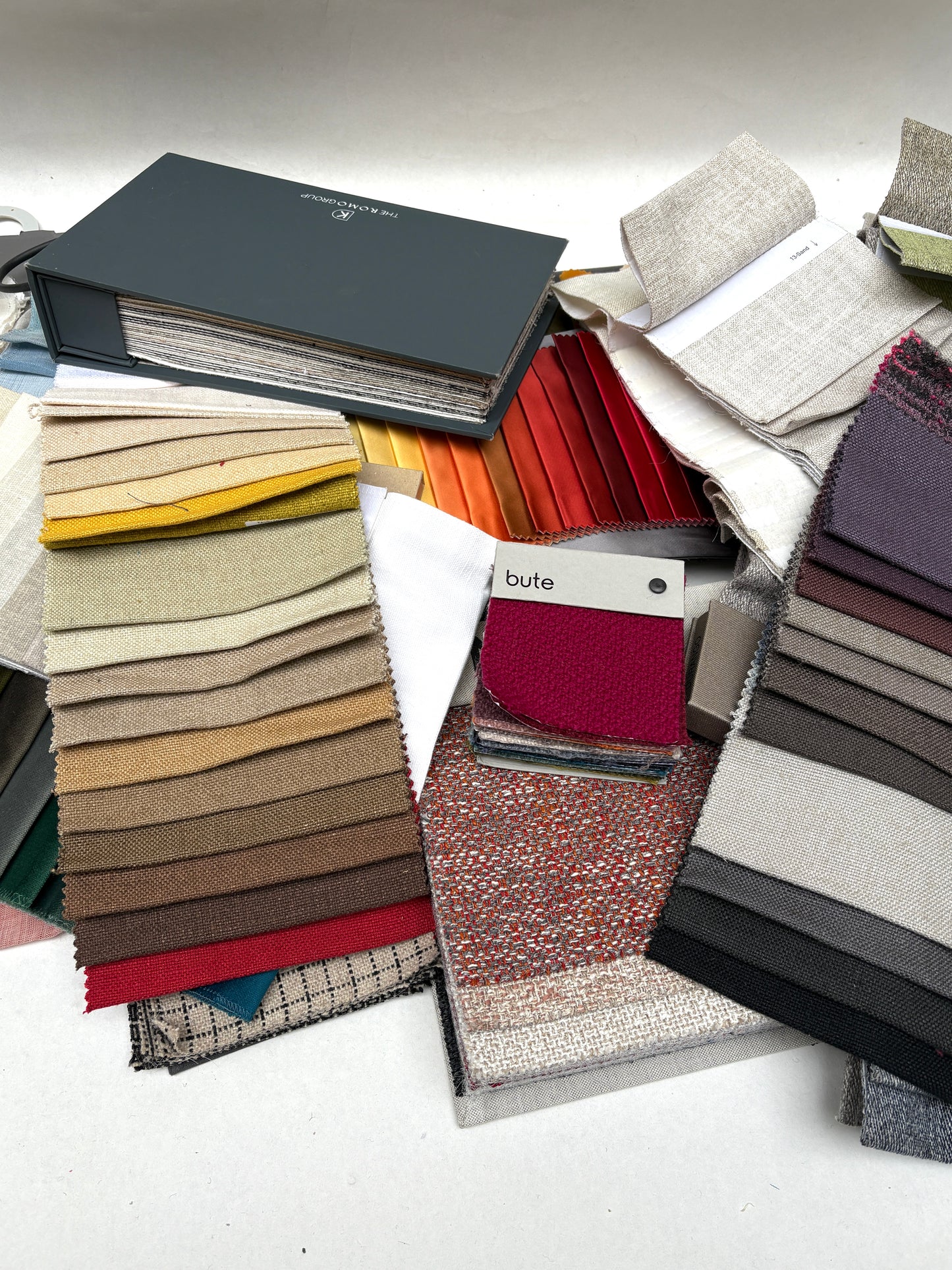 Mixed fabric sample cards are arranged with neutral and bright colour ranges