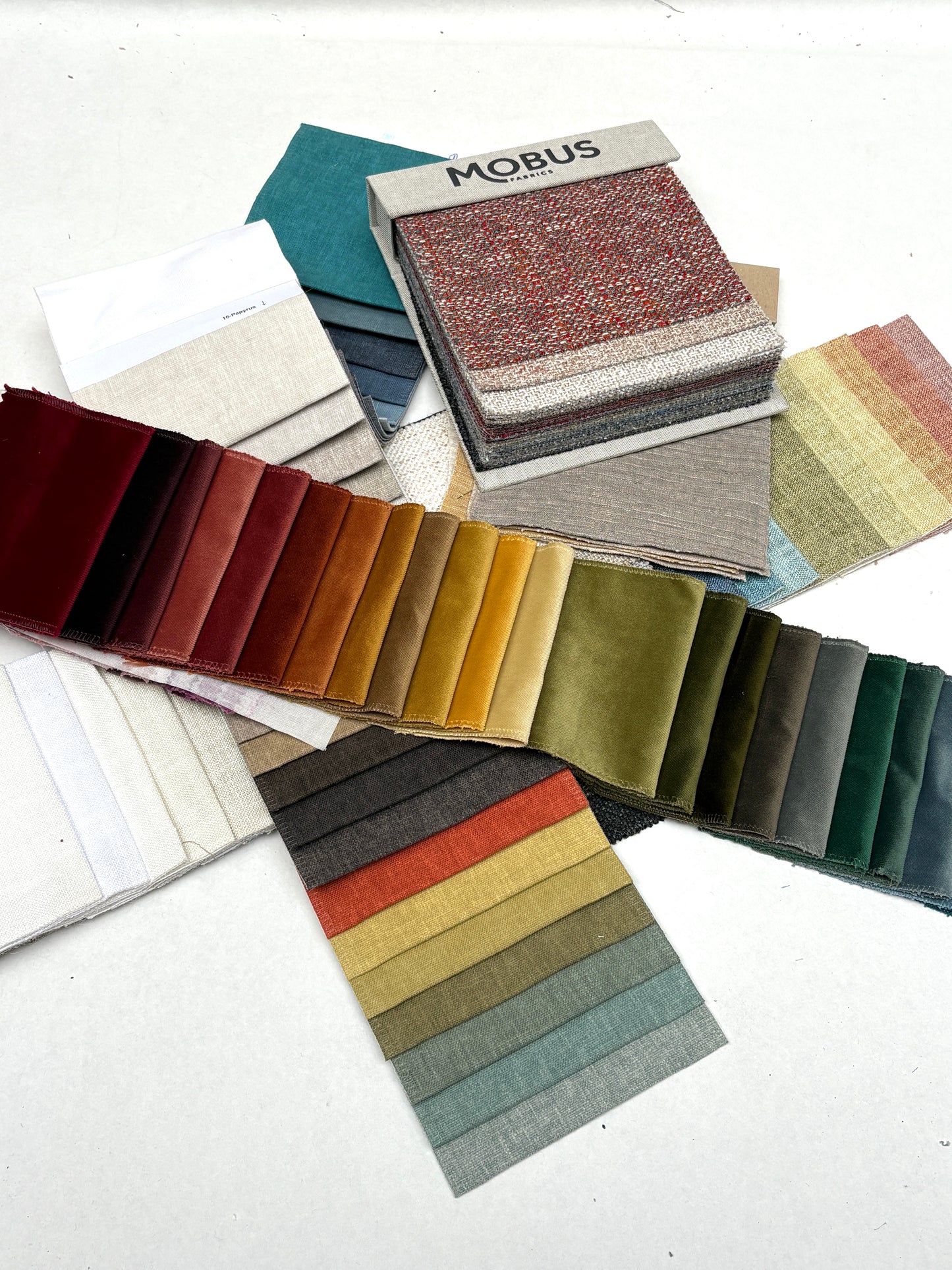Mixed fabric sample cards are arranged with neutral and bright colour ranges