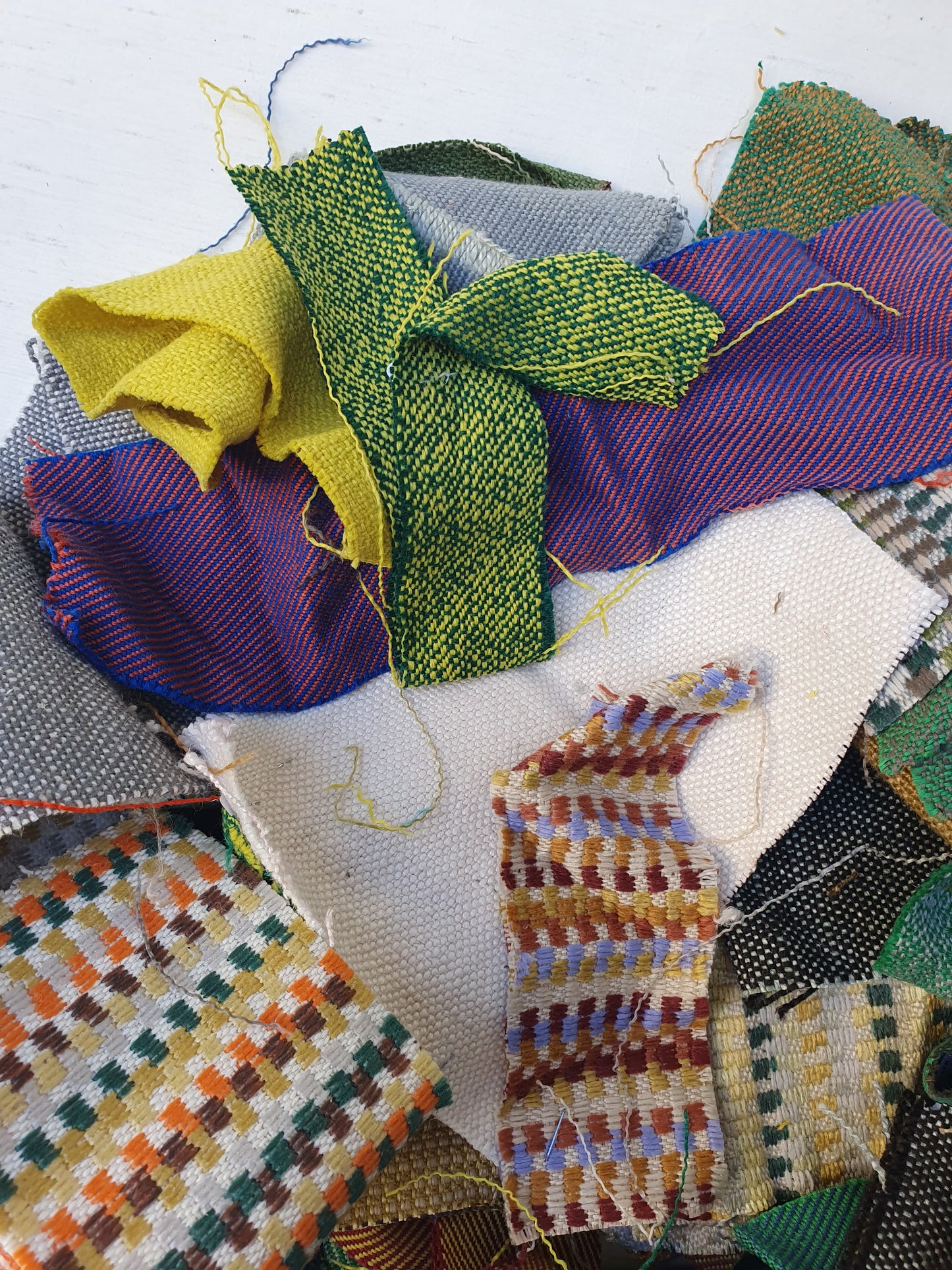 A pile of various rectangular fabric offcuts in different colours and textures.