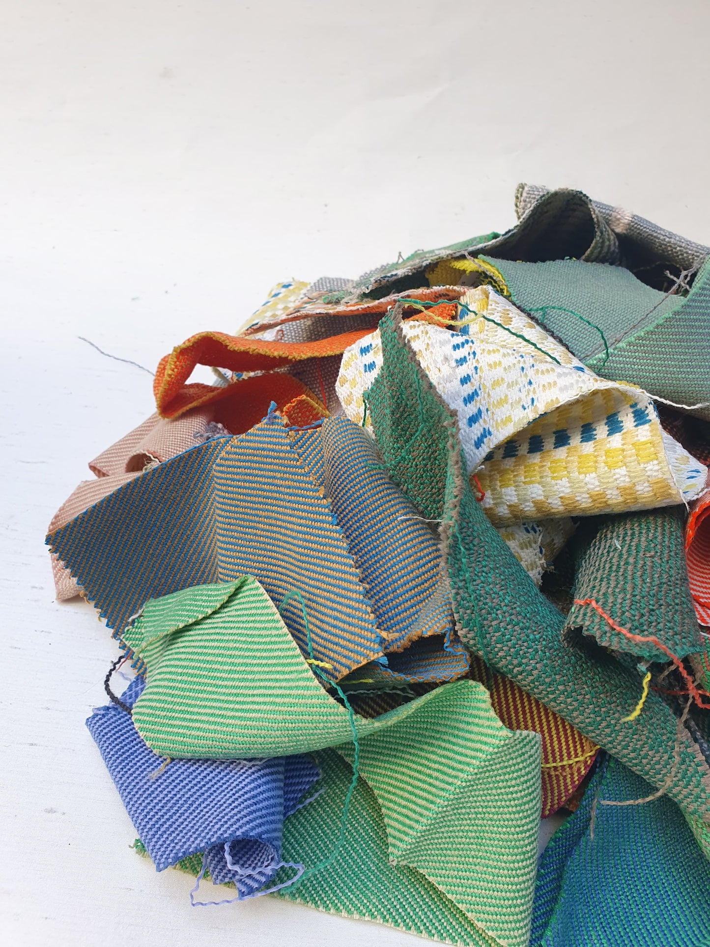 A pile of various rectangular fabric offcuts in different colours and textures.