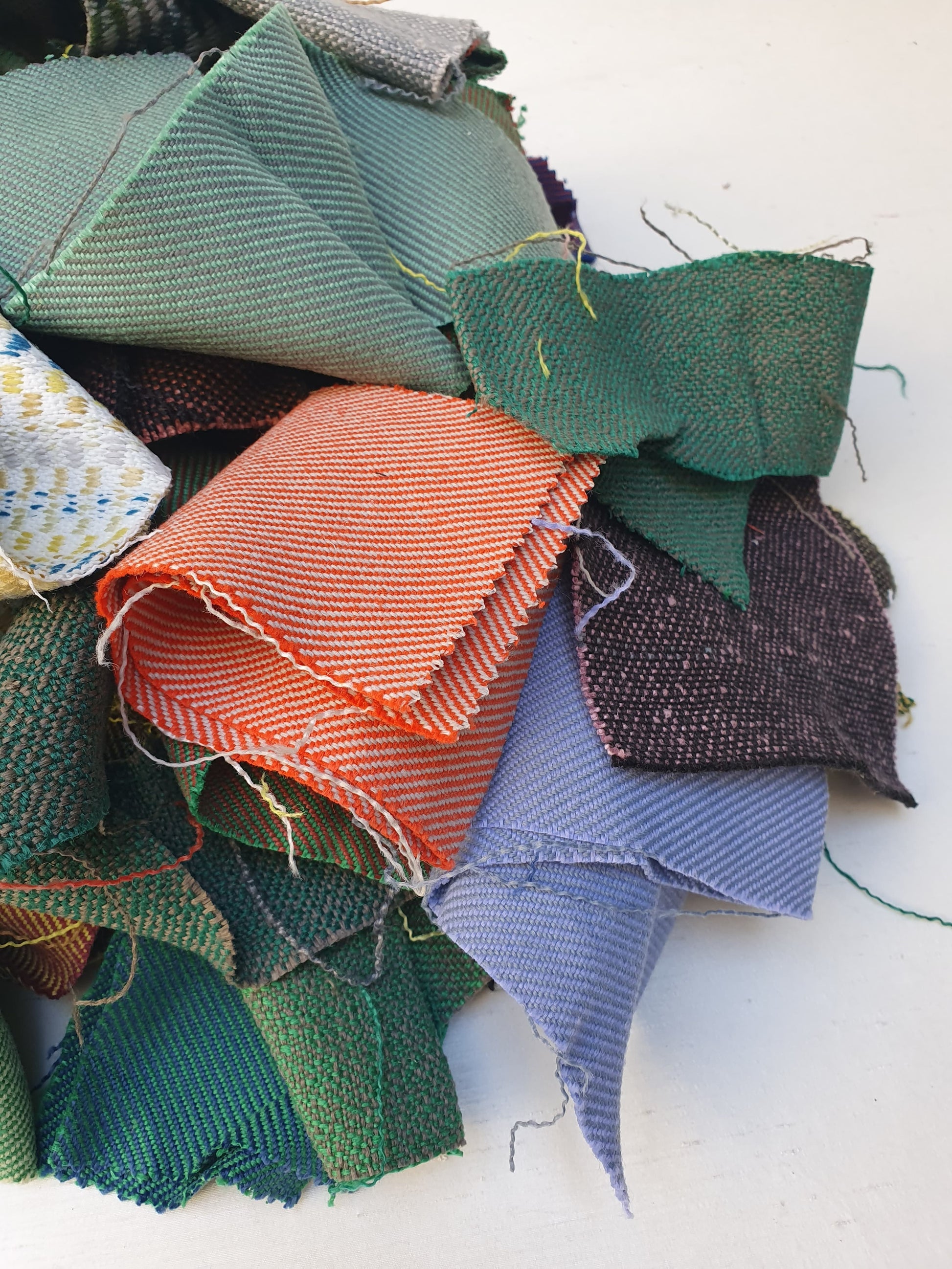 A pile of various rectangular fabric offcuts in different colours and textures.