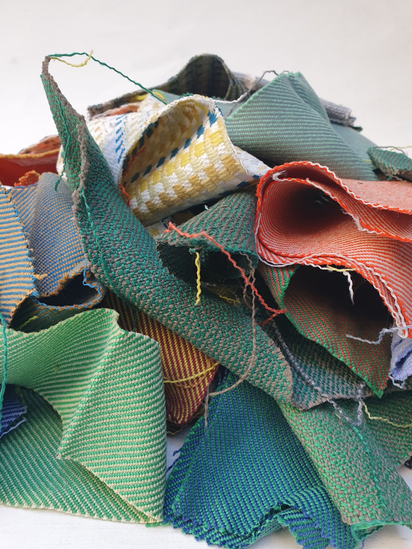A pile of various rectangular fabric offcuts in different colours and textures.