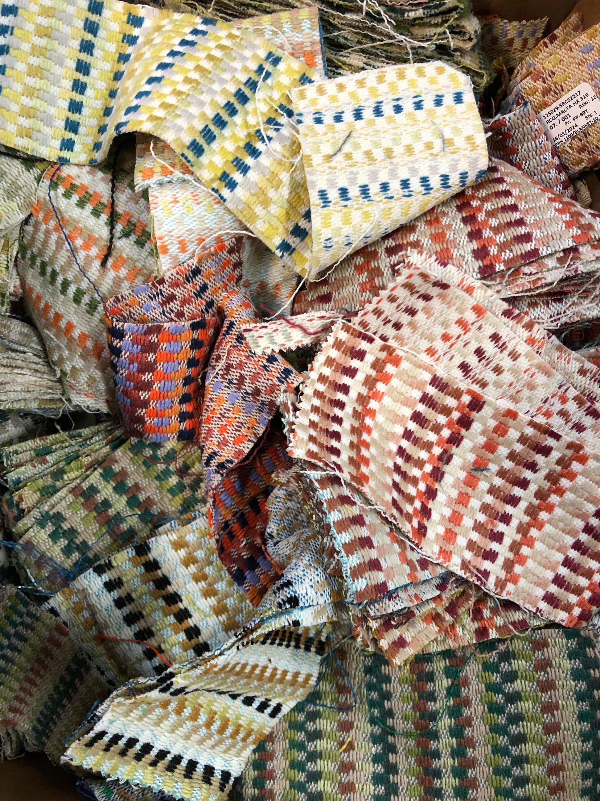 A pile of various rectangular fabric offcuts in different colours and textures.