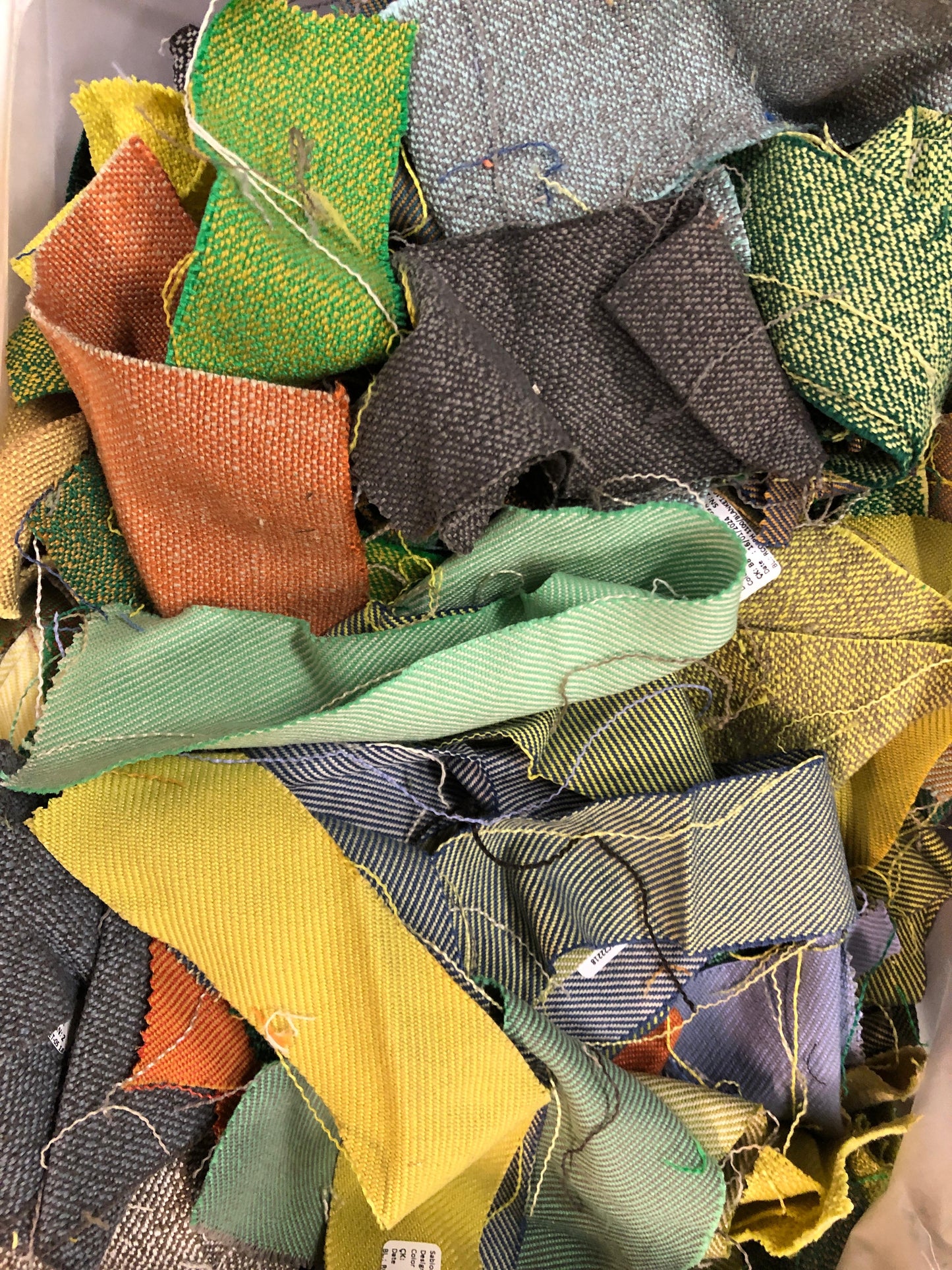 A pile of various rectangular fabric offcuts in different colours and textures.