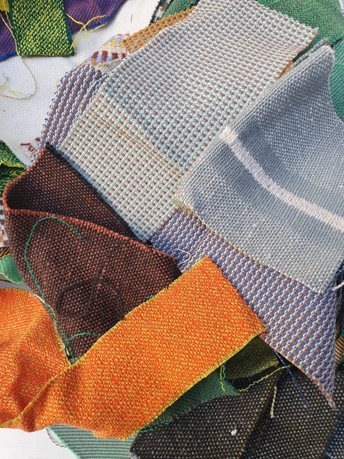 A pile of various rectangular fabric offcuts in different colours and textures.