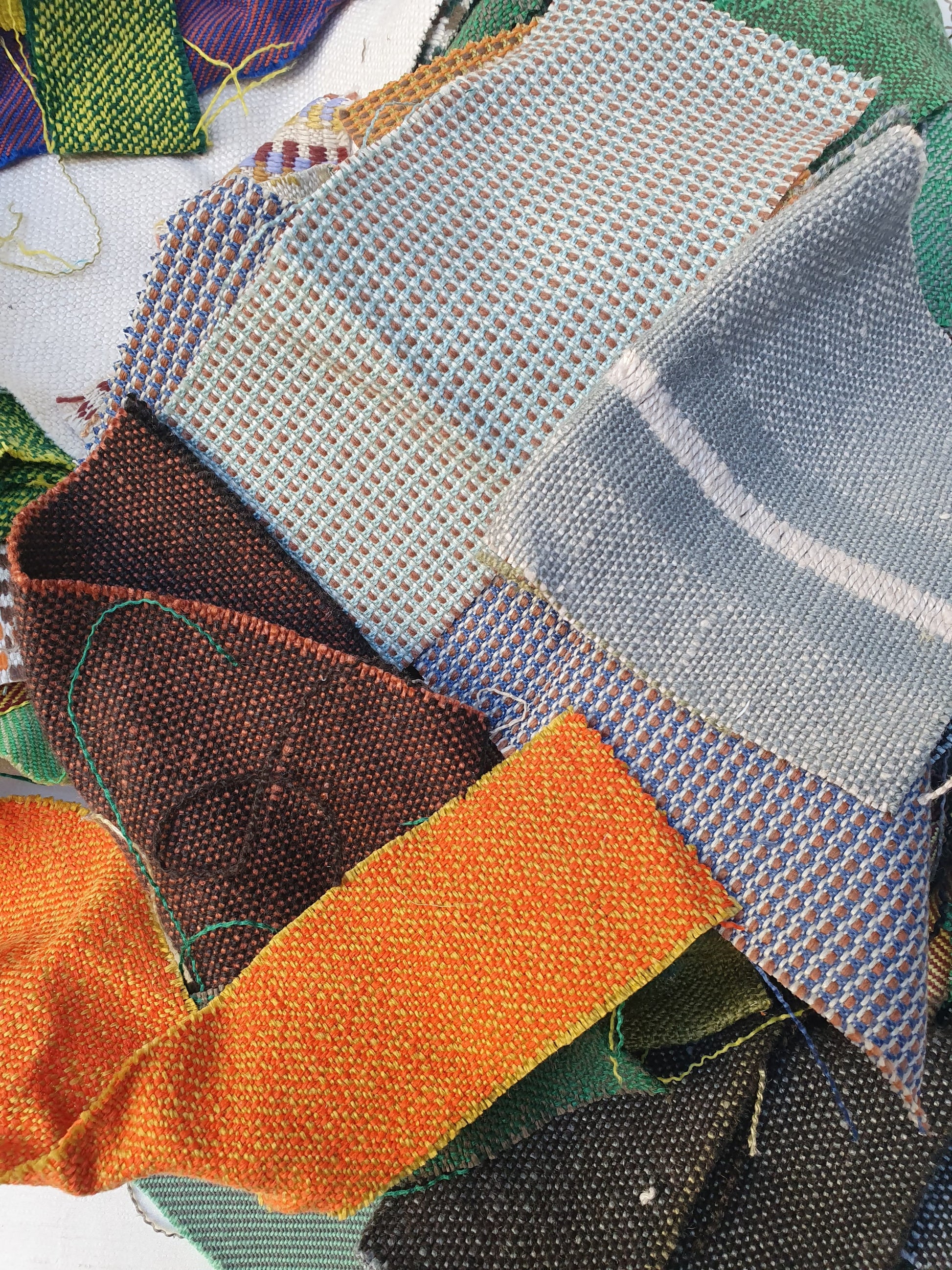 A pile of various rectangular fabric offcuts in different colours and textures.