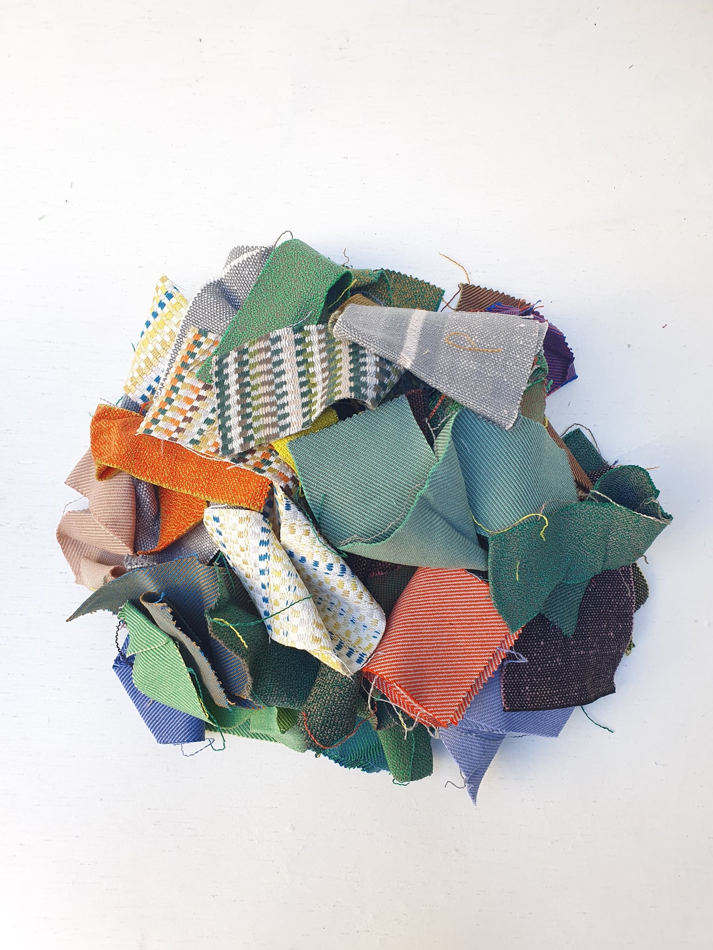 A pile of various rectangular fabric offcuts in different colours and textures.