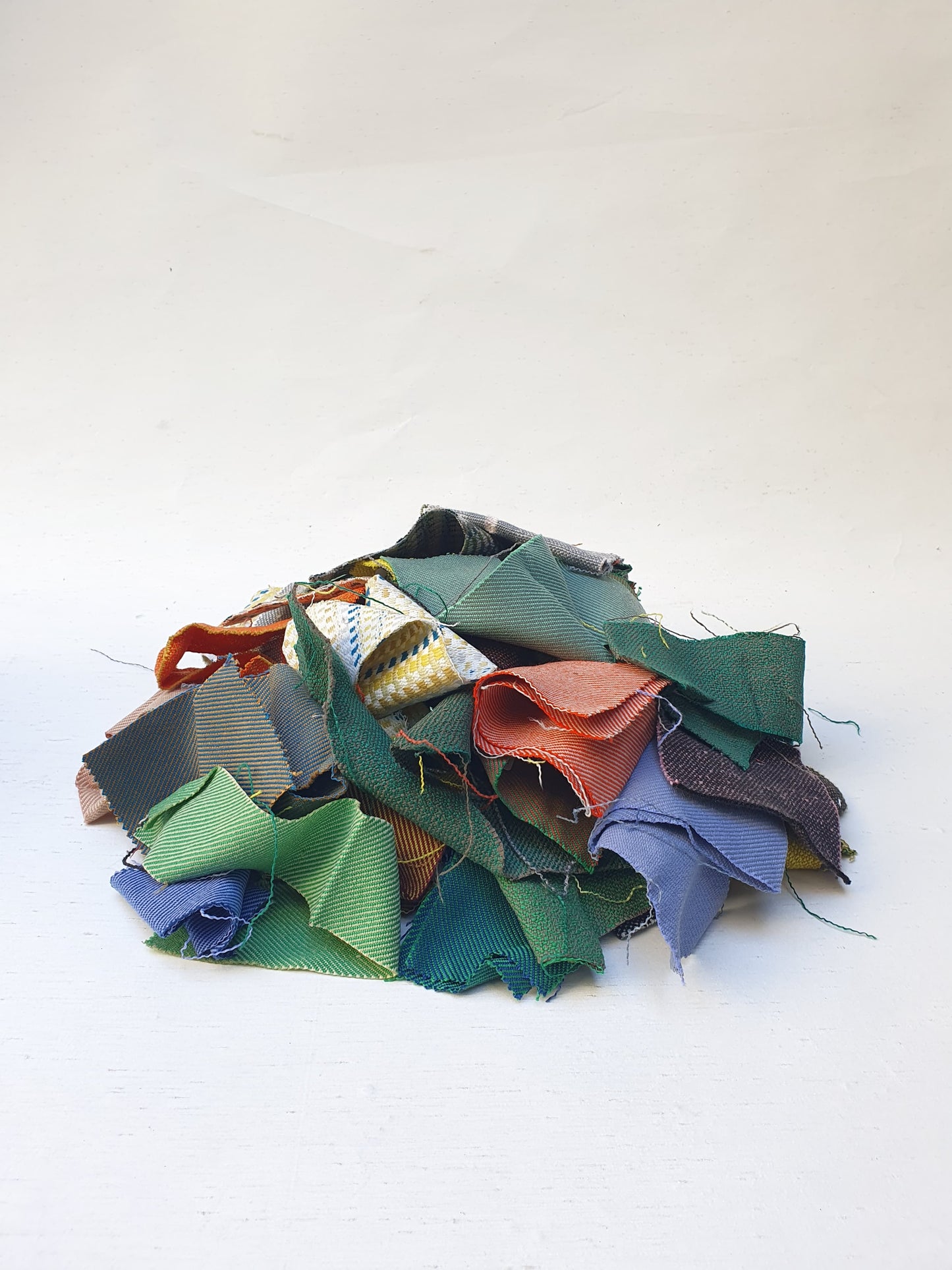 A pile of various rectangular fabric offcuts in different colours and textures.