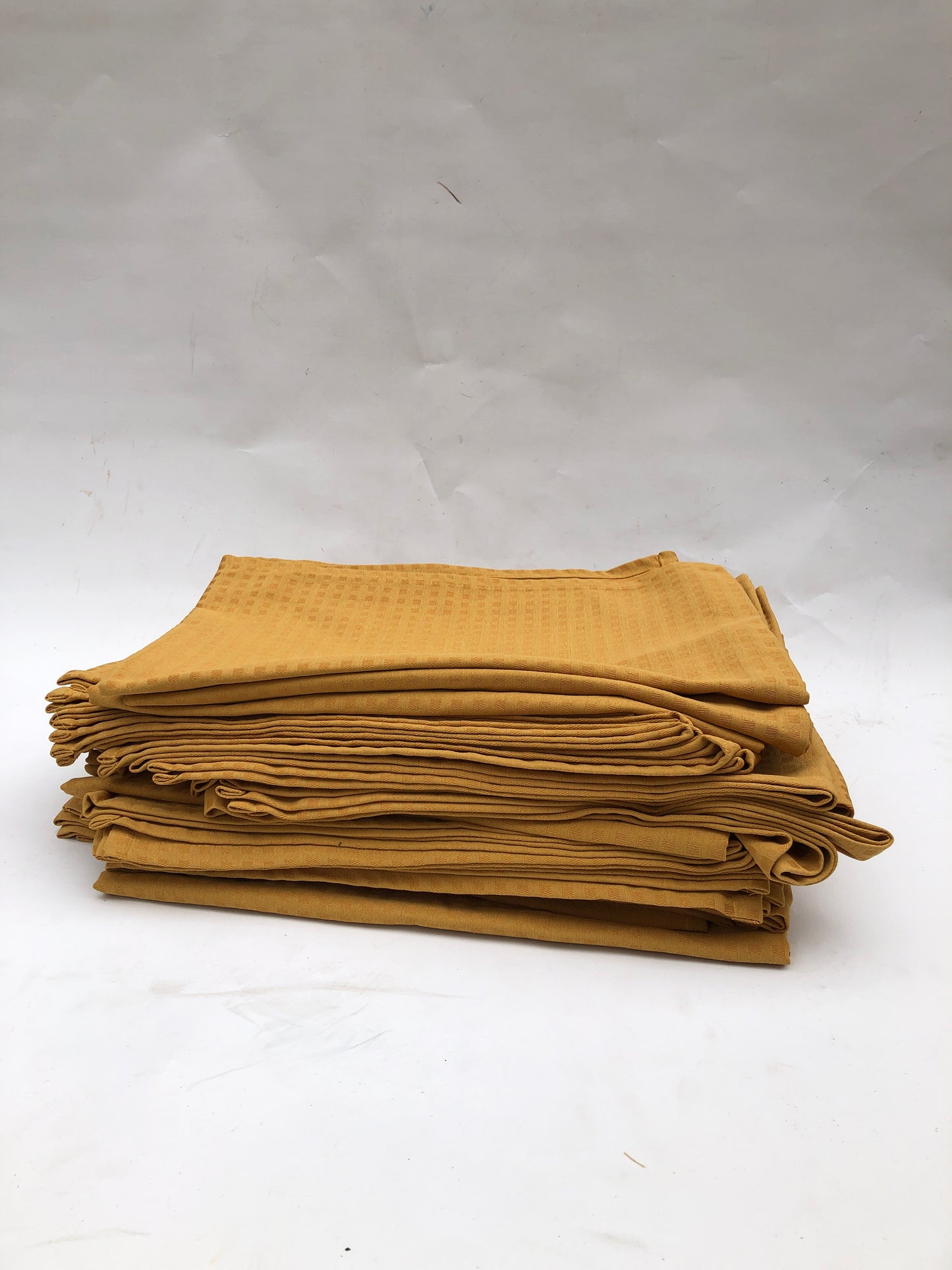 Stack of table runner fabric in mustard yellow with chequered patterns