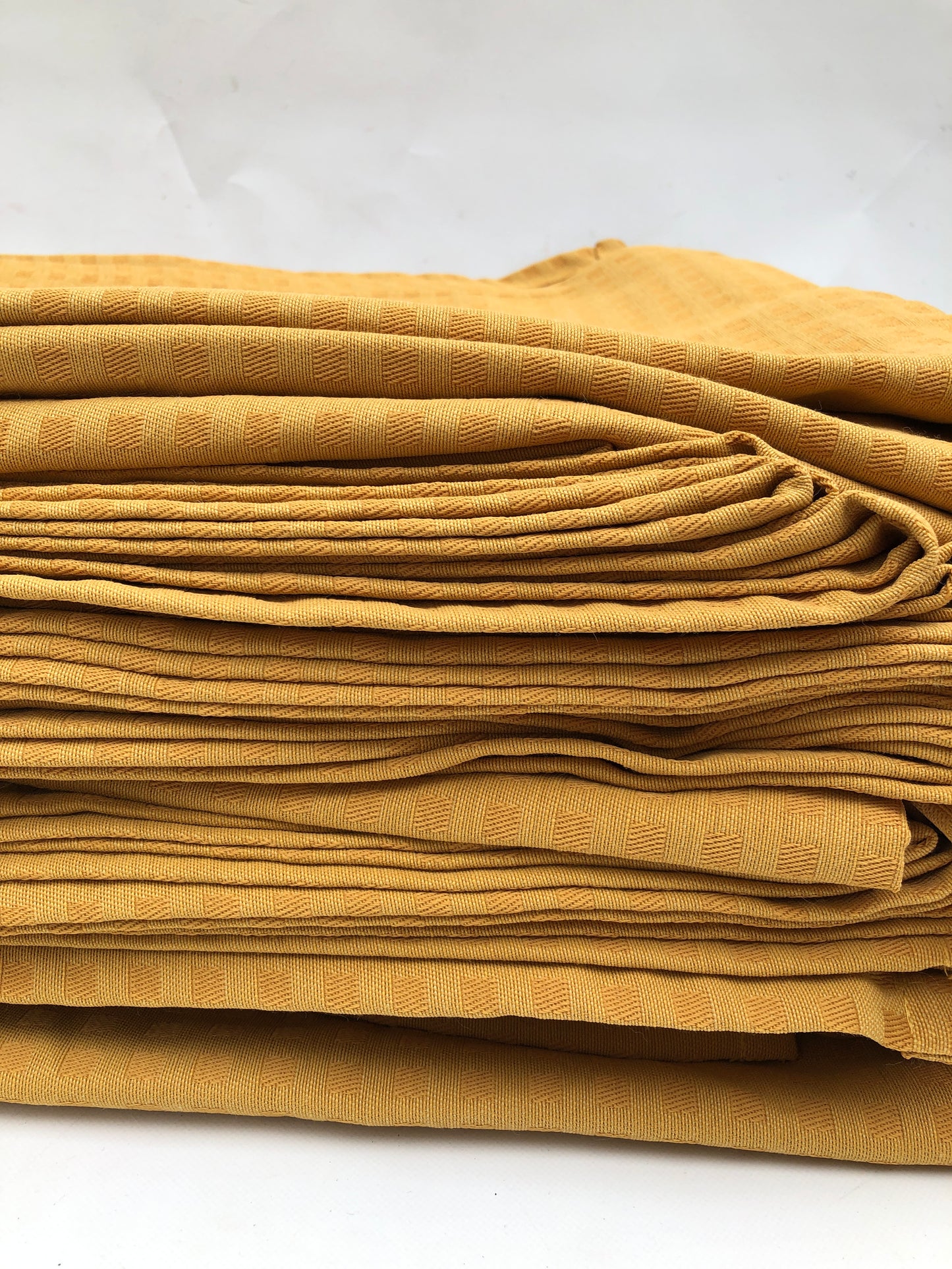 Stack of table runner fabric in mustard yellow with chequered patterns