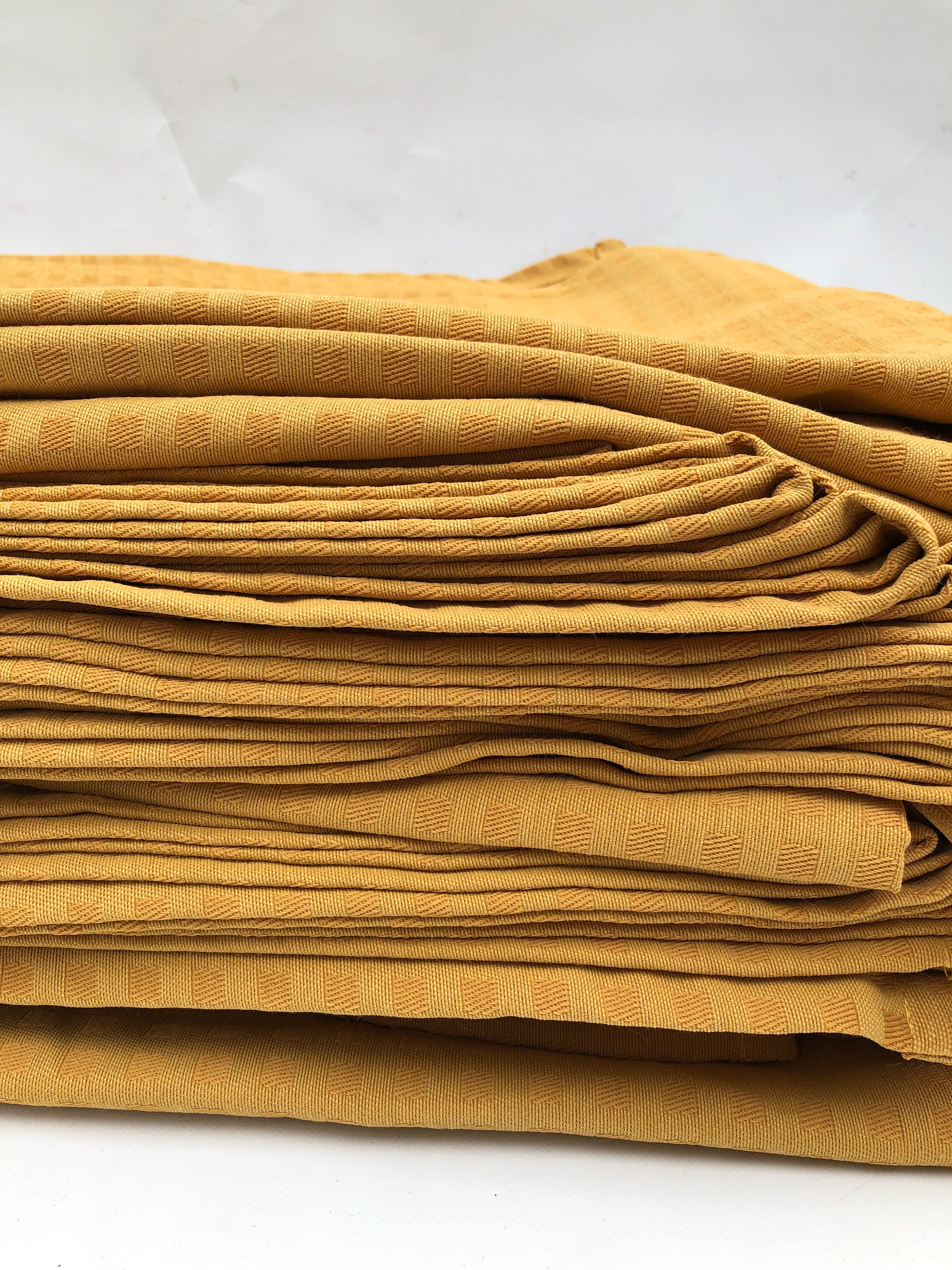 Stack of table runner fabric in mustard yellow with chequered patterns