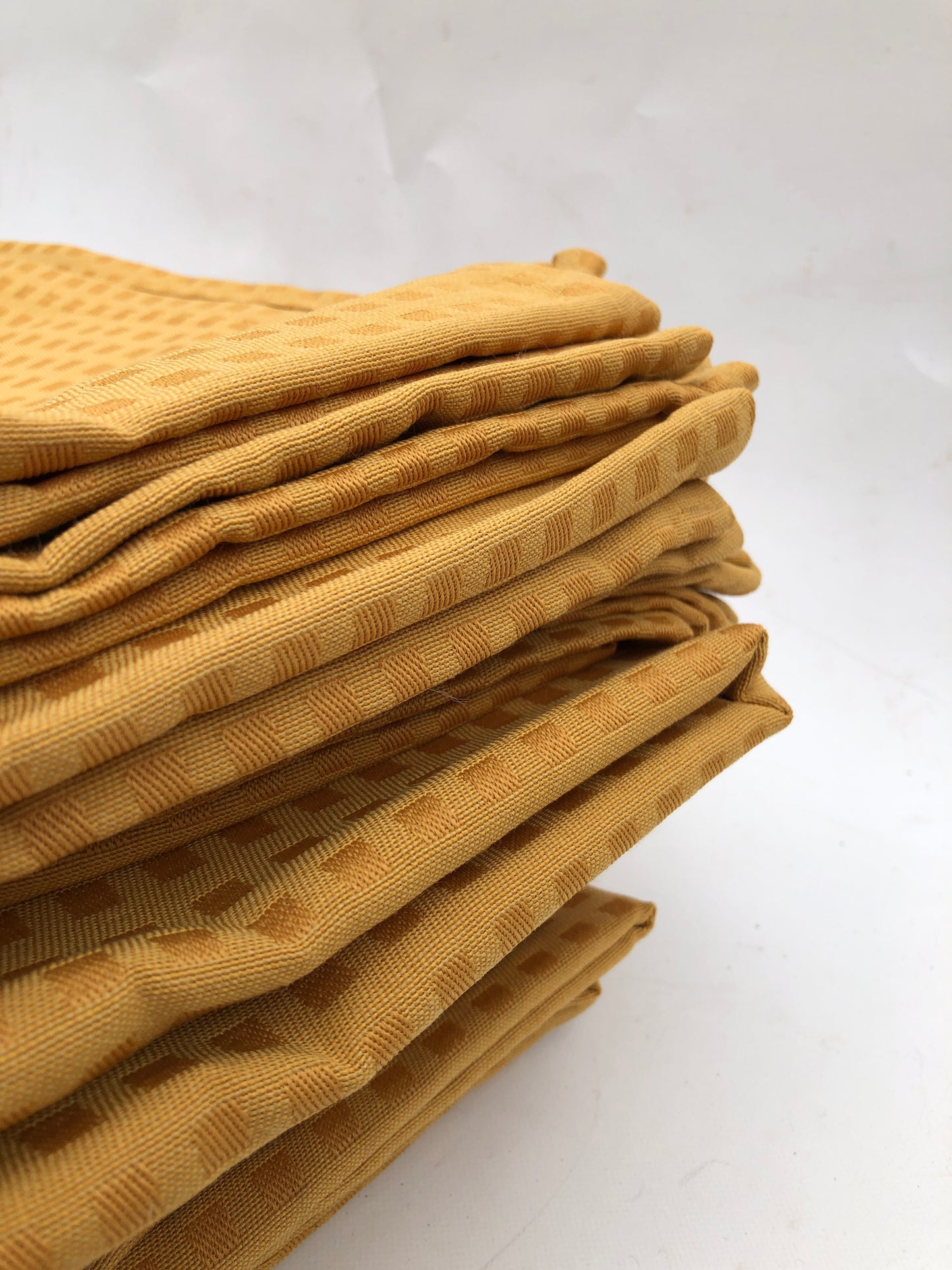 Stack of table runner fabrics in mustard yellow with chequered patterns