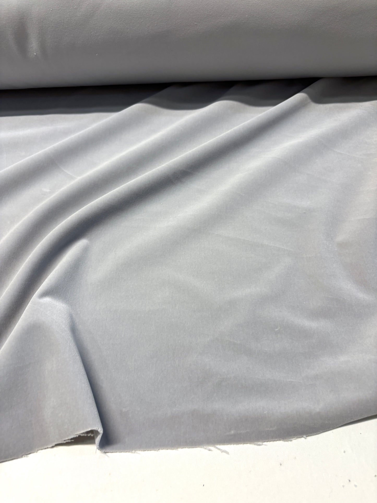 Close-up of rolled silver grey velvet fabric with soft texture 
