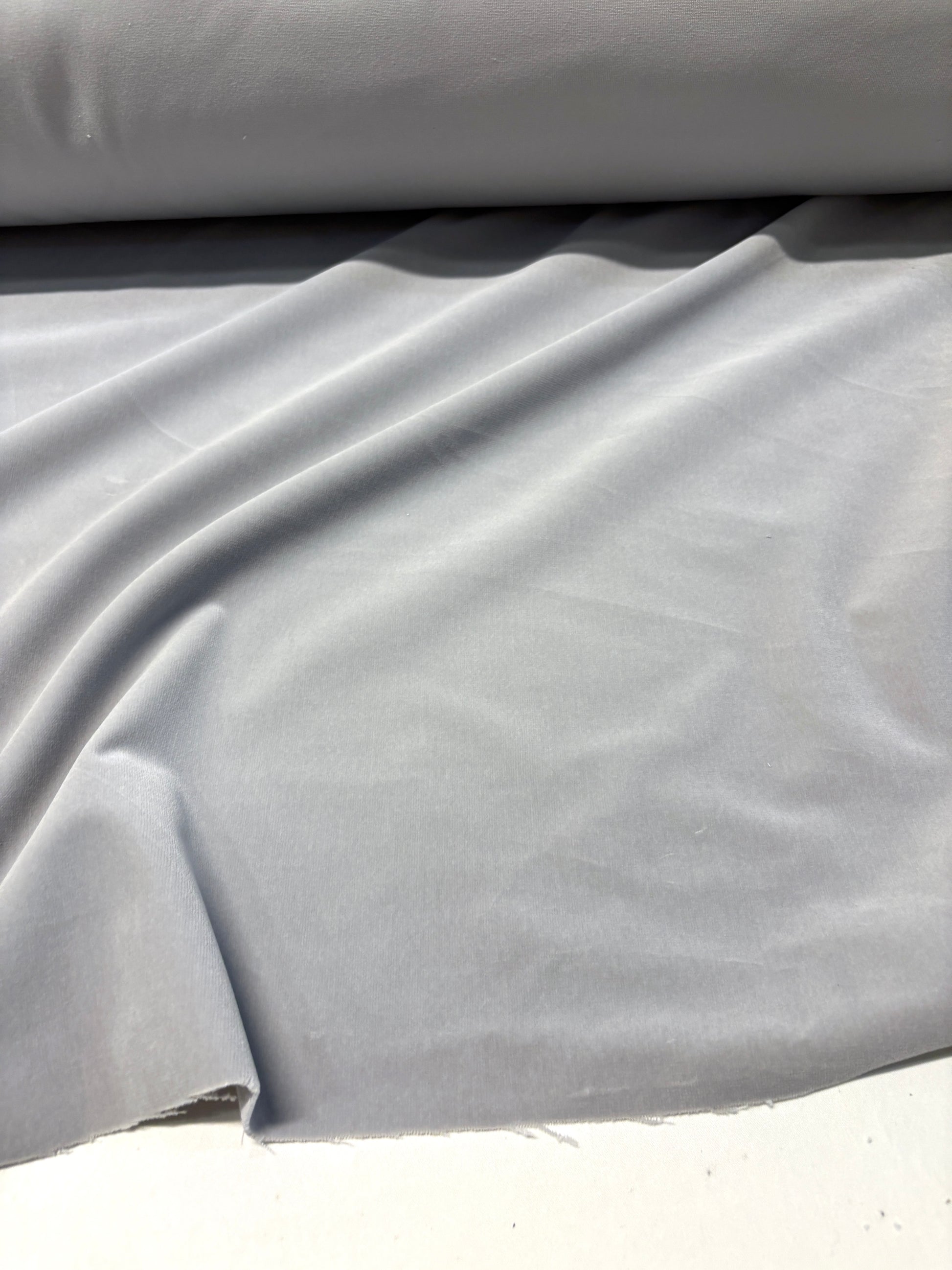 Close-up of rolled silver grey velvet fabric with soft texture 