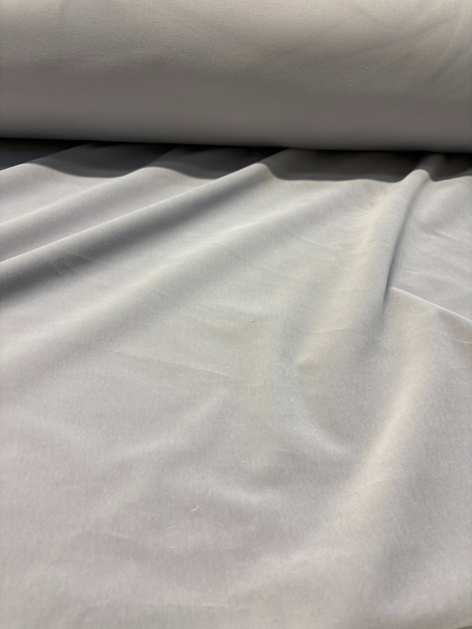 Close-up of rolled silver grey velvet fabric with soft texture 