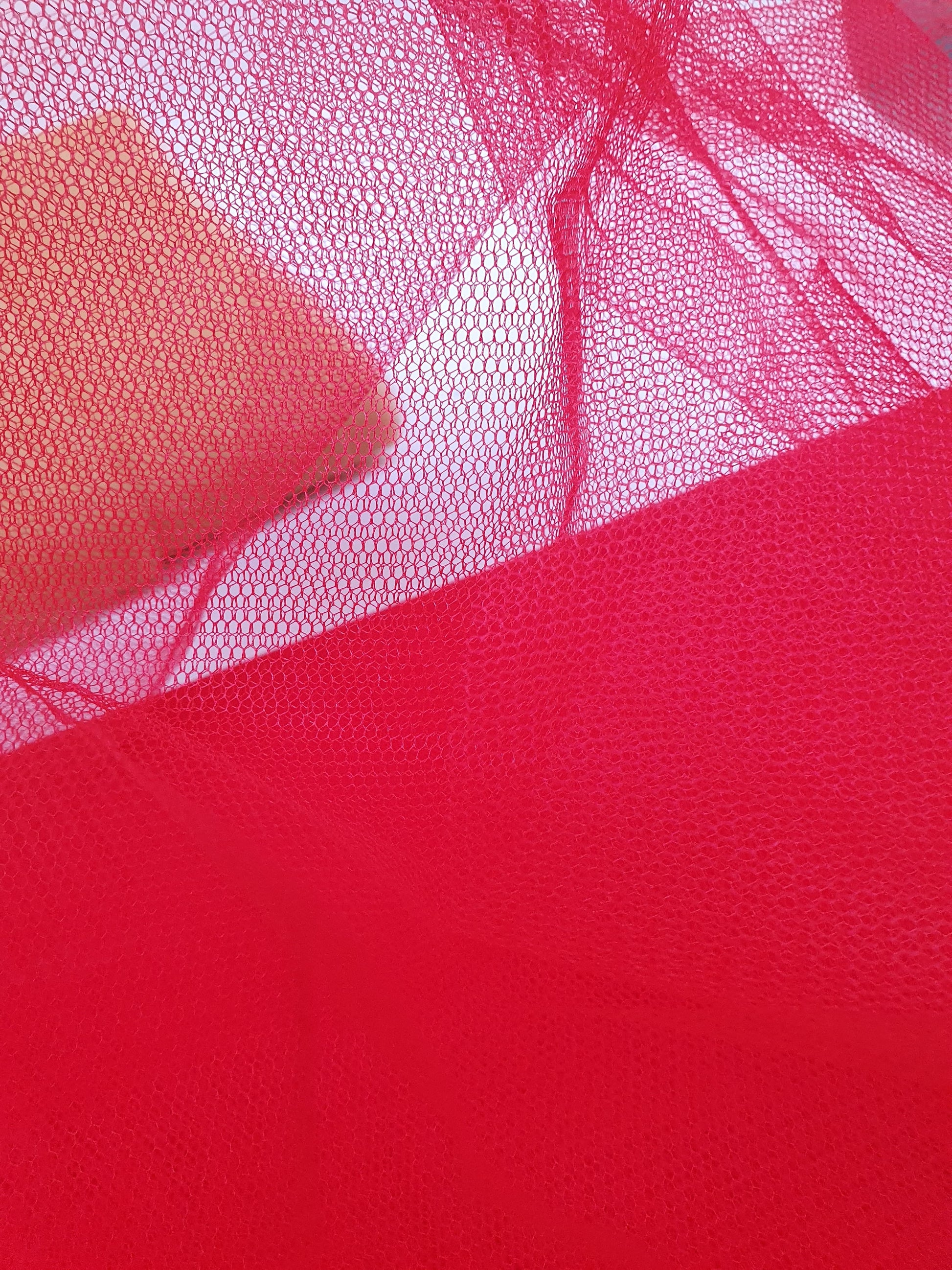A close-up of voile tulle fabric in red, showcasing its breathable net texture.