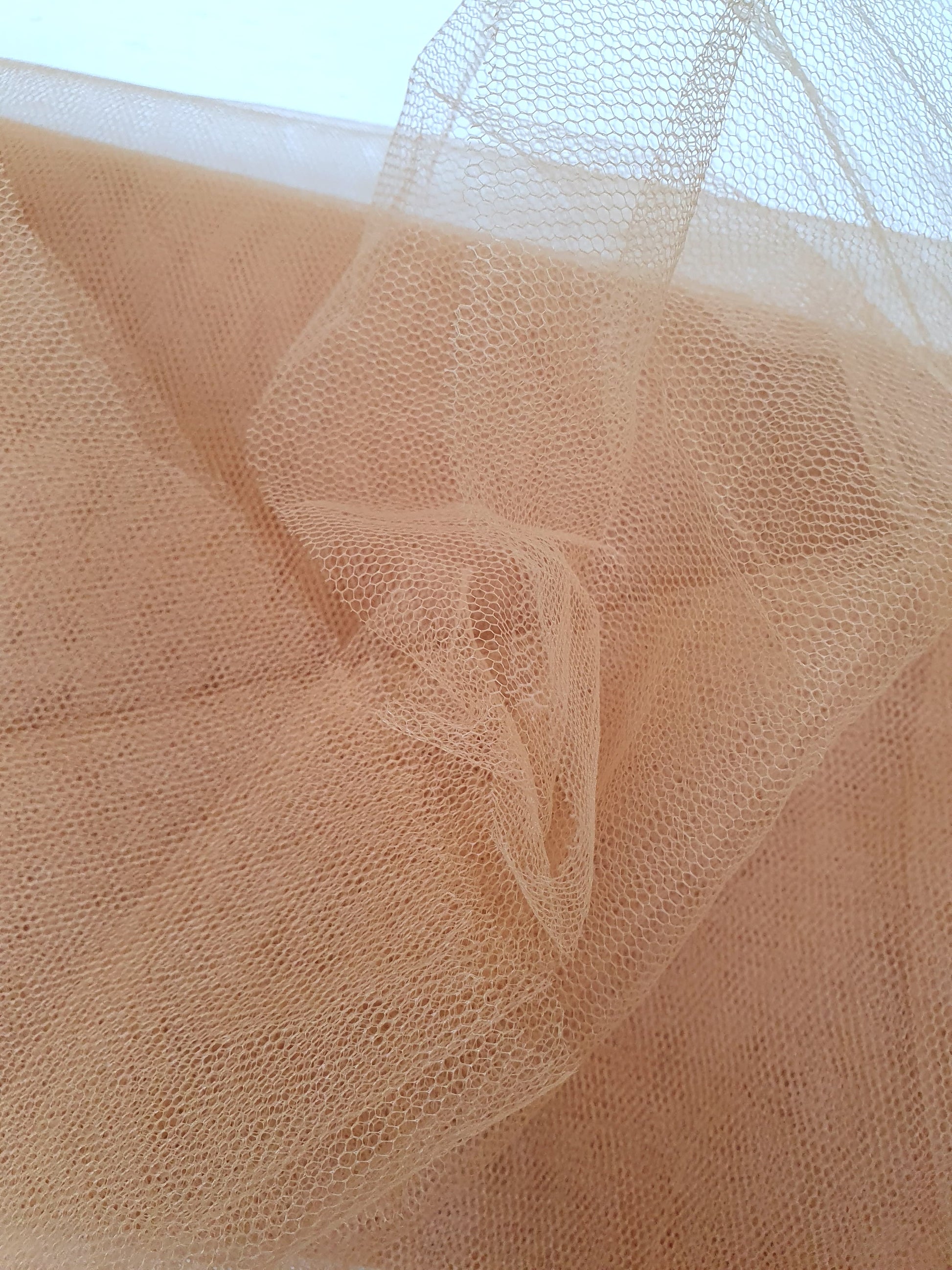 A close-up of voile tulle fabric in cinnamon, showcasing its breathable net texture.