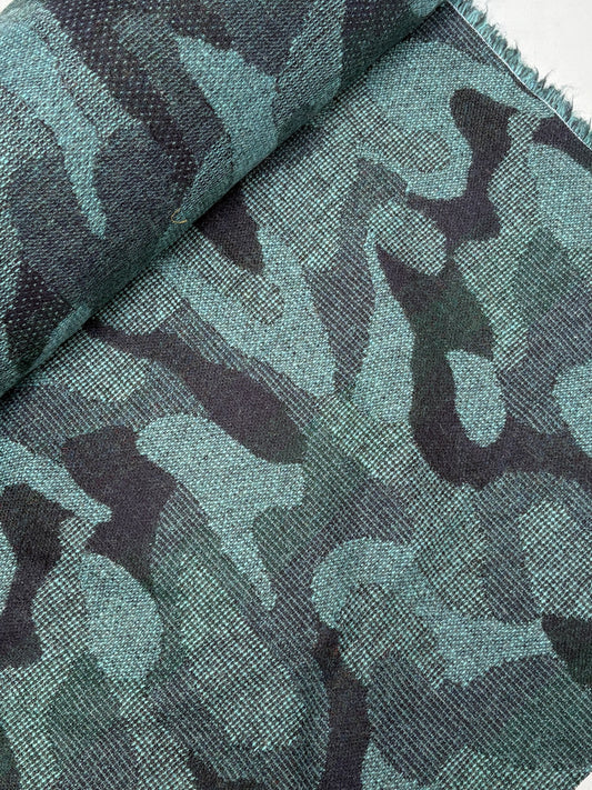 Close-up of a rolled camouflage-pattern jacquard-weave fabric in green and black