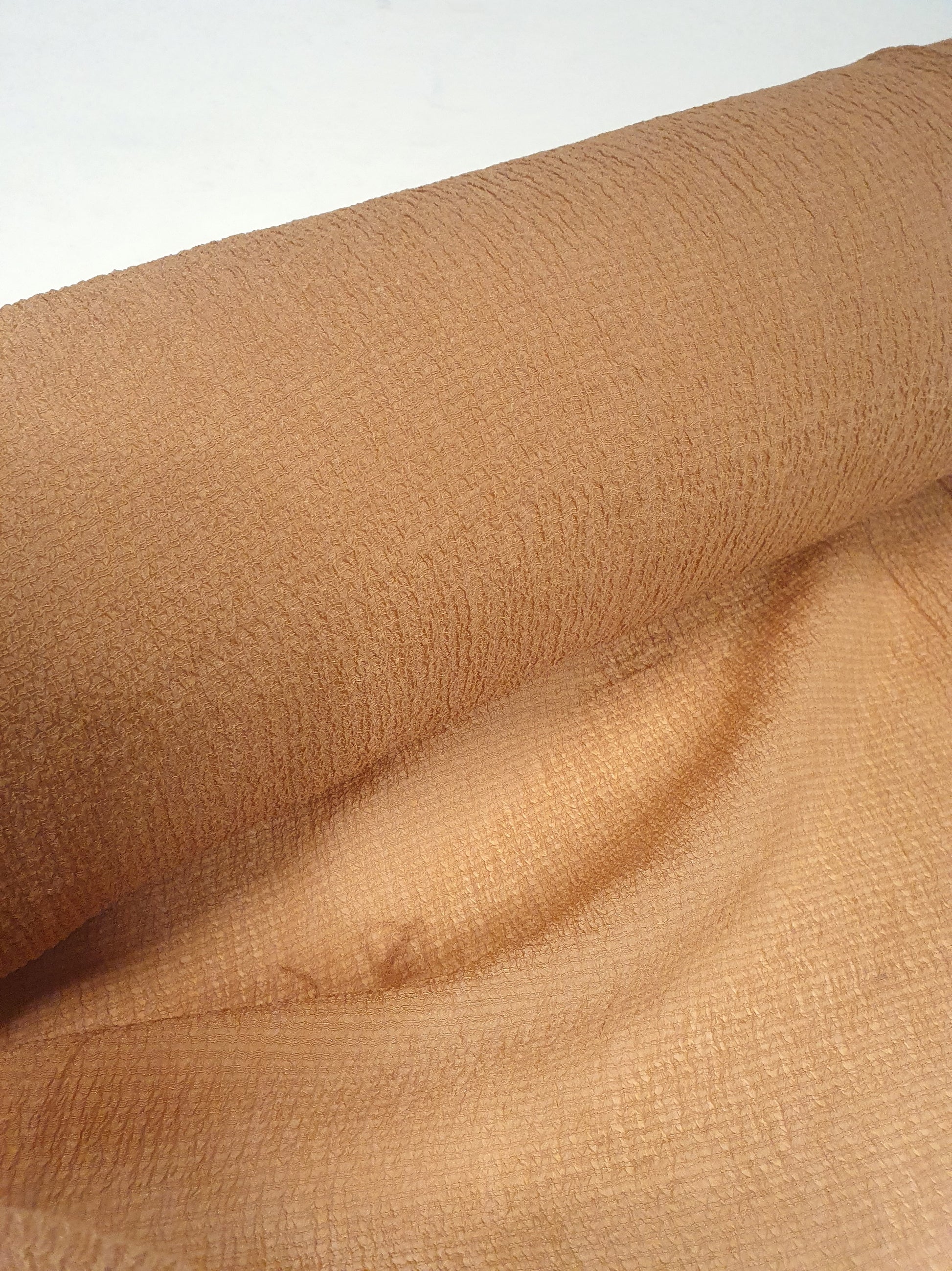 A close-up of wrinkled fabric in a peach colour, showing the texture