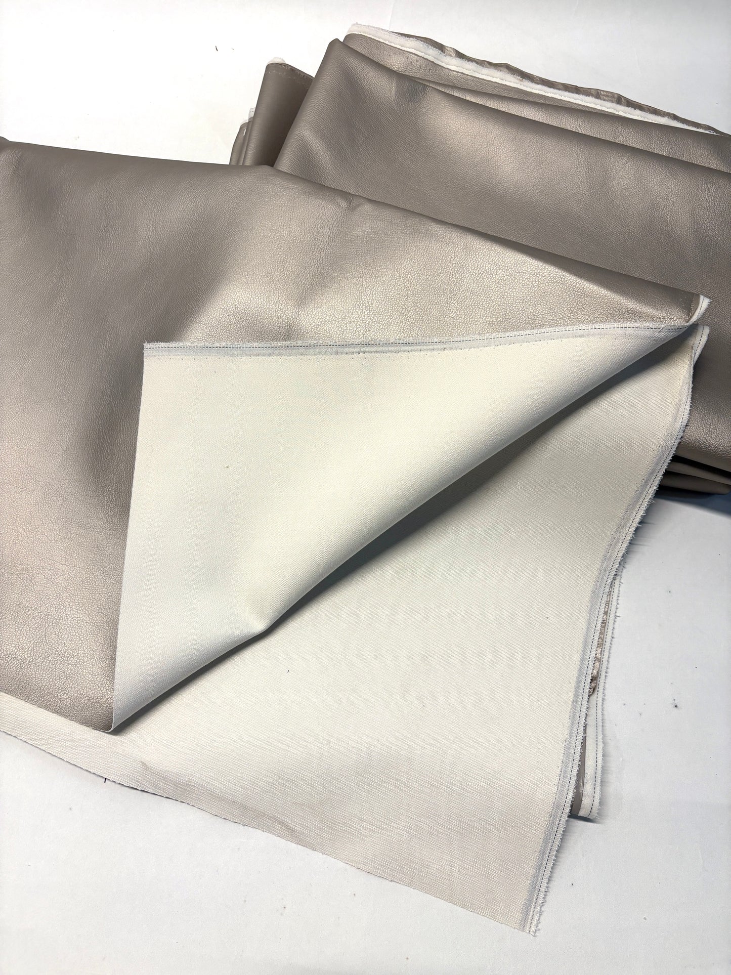 Stack of faux leather in metallic bronze with white backside 